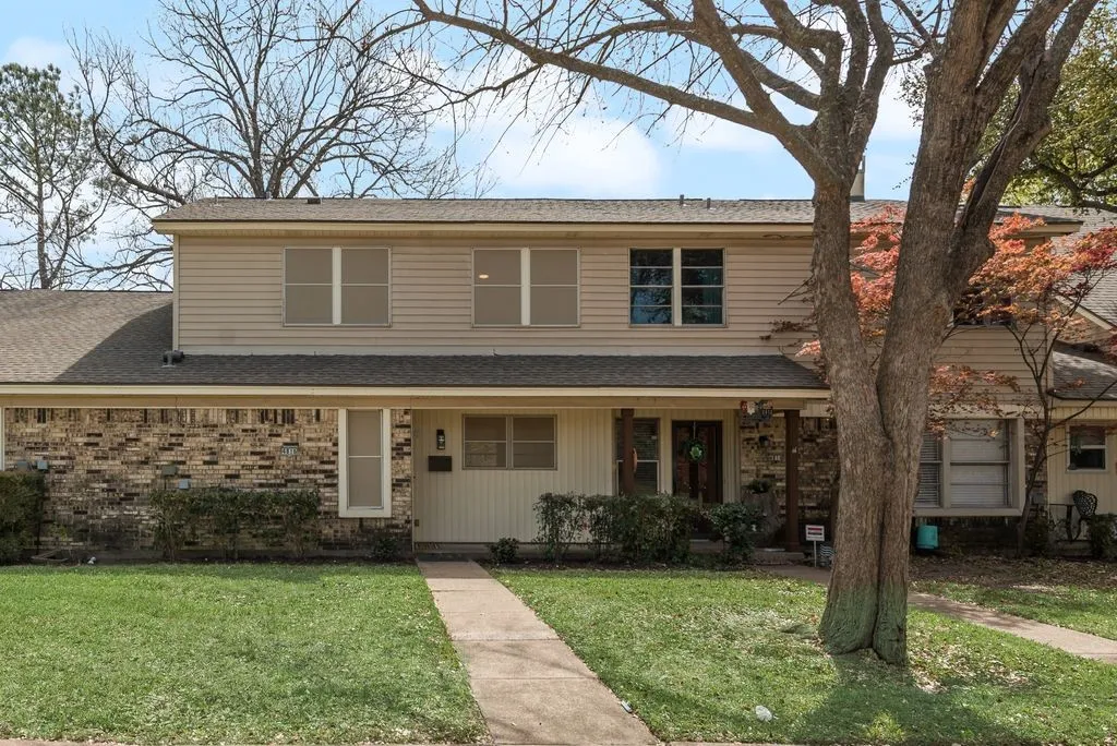 Two-story residence featuring brick and siding exterior, a front walkway, and mature trees