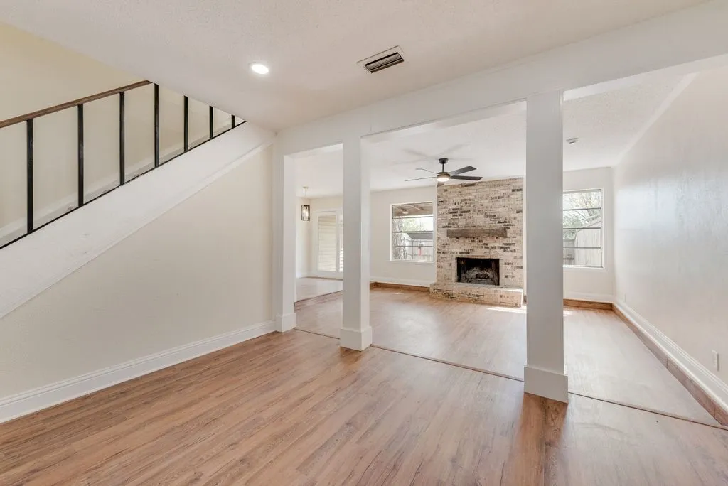 Wood-finish flooring throughout, with a staircase featuring a black metal railing
