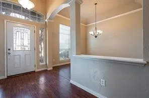 Foyer featuring arched walkways, wood finished floors, baseboards, and a chandelier