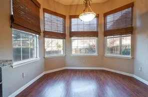 Spare room with healthy amount of natural light, wood finished floors, and baseboards