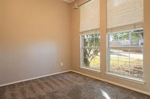 Unfurnished room featuring baseboards and dark carpet