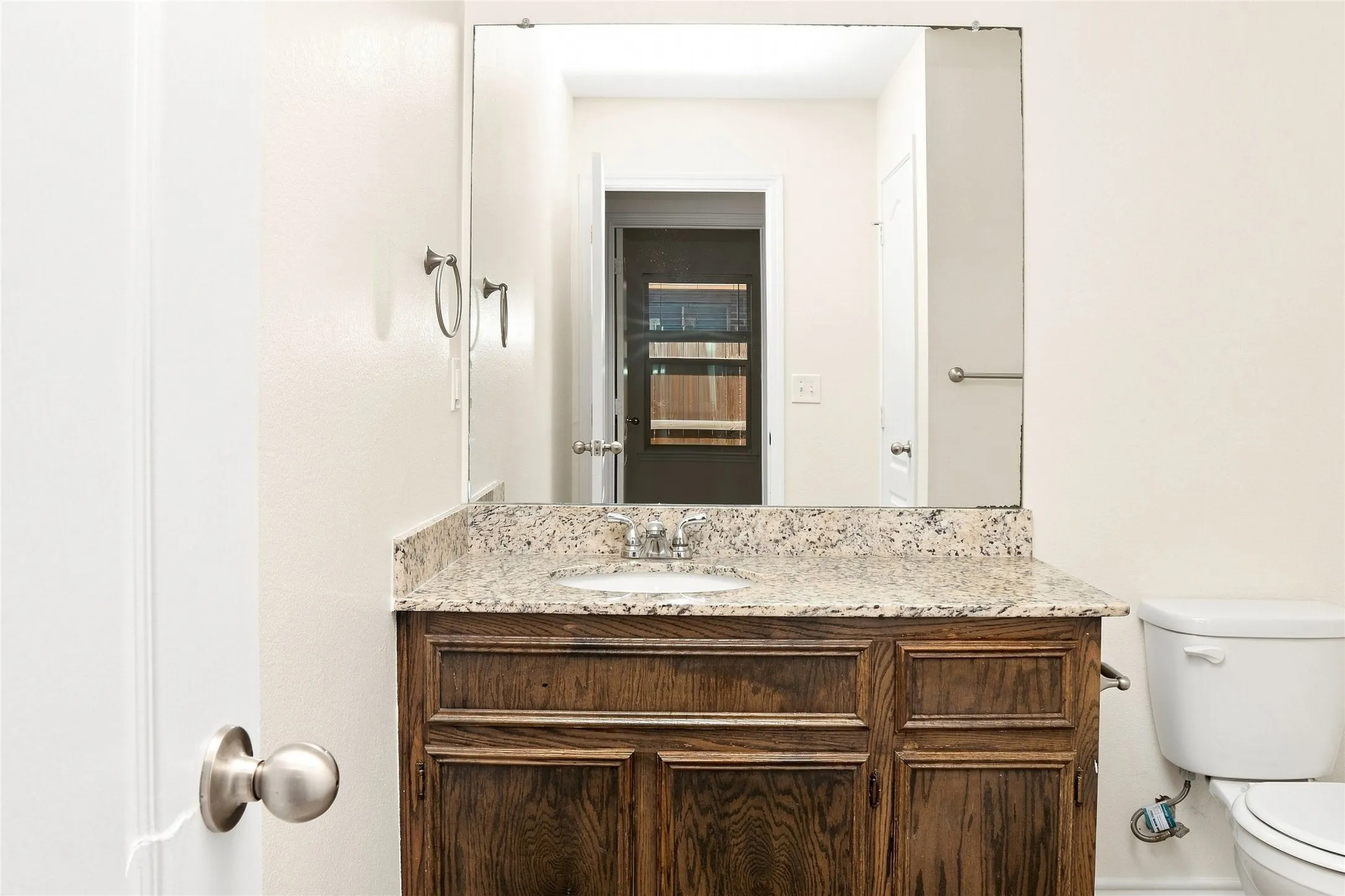 Wood-finish vanity with a granite countertop, undermount sink, and brushed nickel hardware