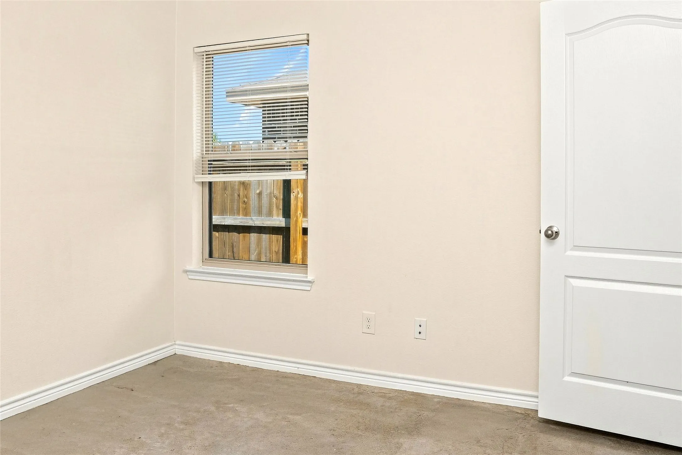 White painted walls, a single window with blinds, and a white interior door