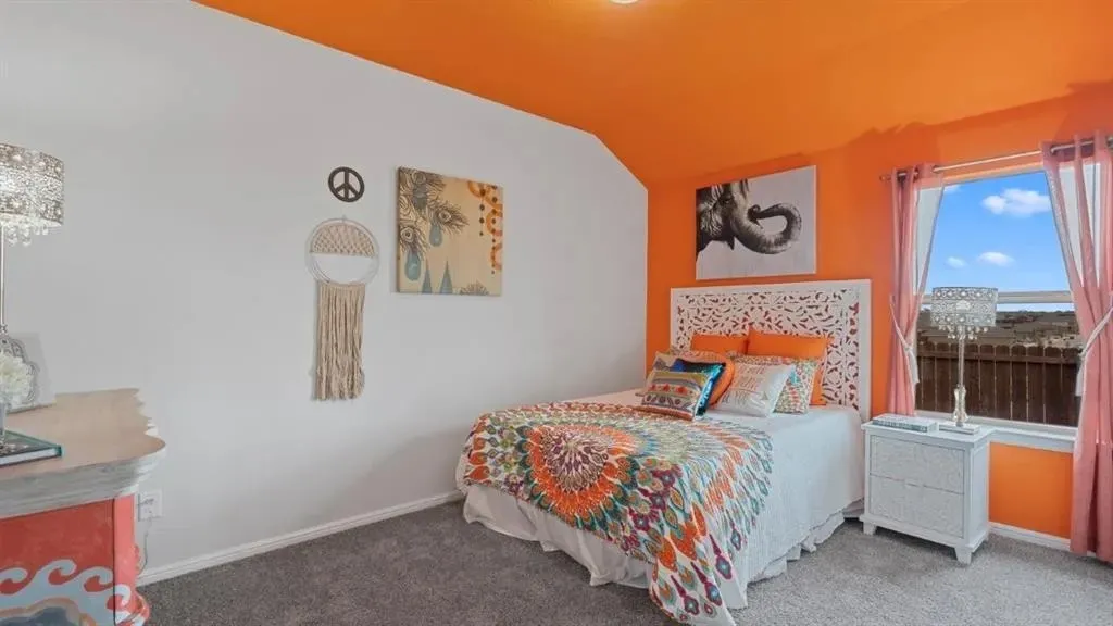 Carpeted flooring, window with exterior scenery, white wall finishes, and an orange accent wall