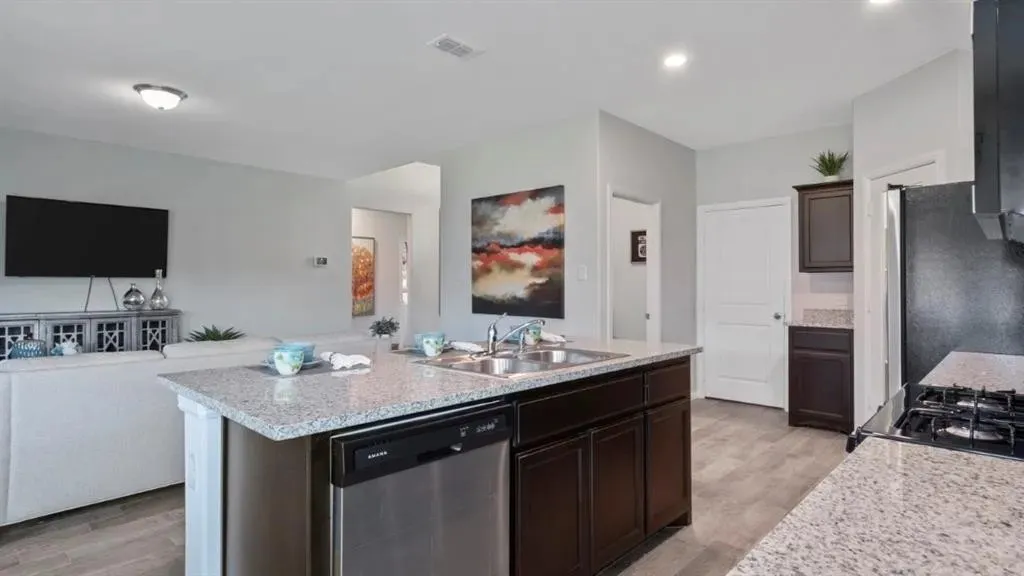 Kitchen island with integrated stainless steel dishwasher, dual basin sink, and granite countertops