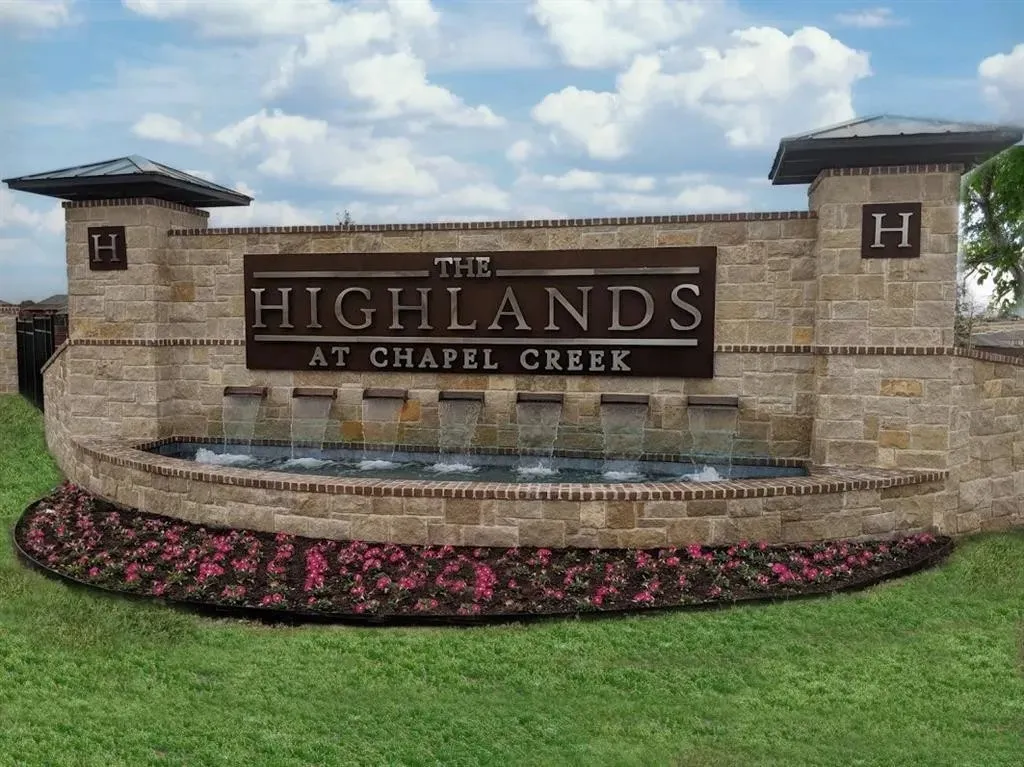 Stone and brick entry monument featuring a multi-tiered water feature, integrated signage, and decorative landscaping