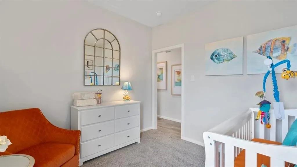 Plush carpet flooring, neutral wall tones, and a doorway leading to an additional space