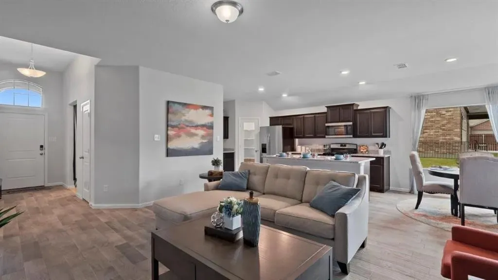 Wood-finish flooring throughout, kitchen with dark wood cabinetry, white countertops, and stainless steel appliances