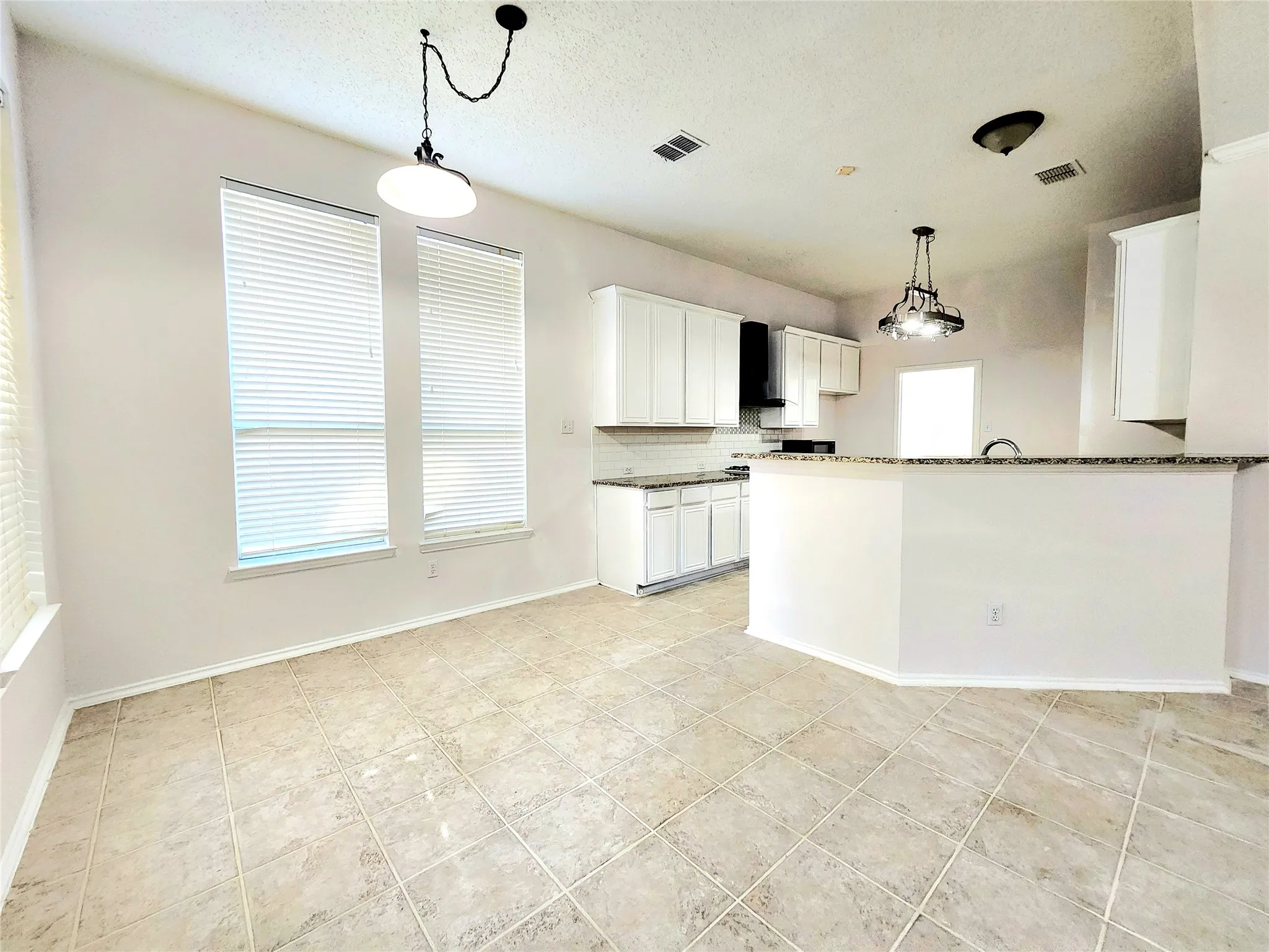 Spacious room with large windows, tile flooring, and a contemporary pendant light fixture