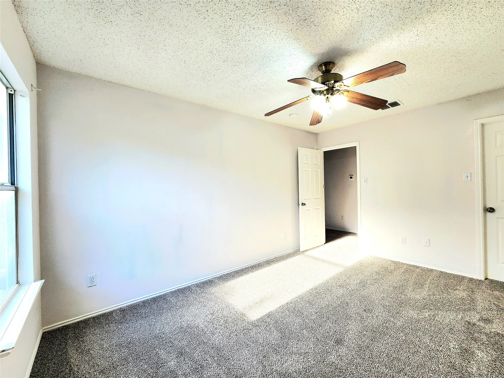 Wall-to-wall carpeting and a ceiling fan with integrated lighting