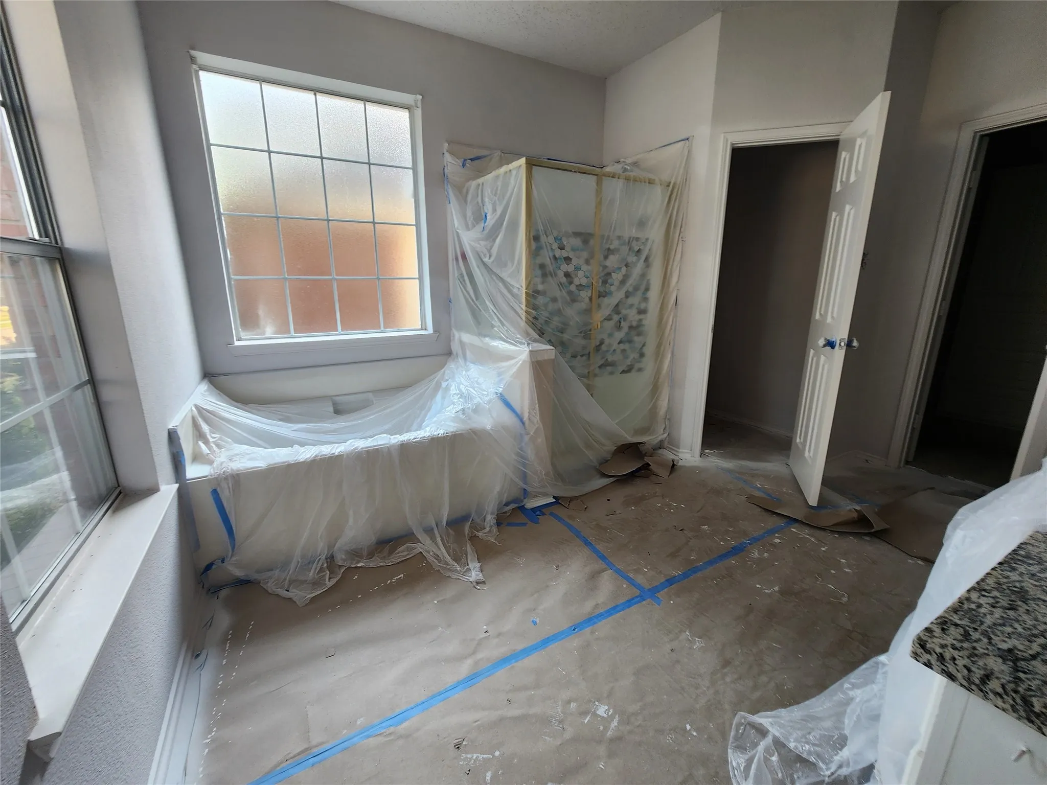 Alcove bathtub with surrounding windows, separate shower enclosure with patterned tile, and paneled interior doors