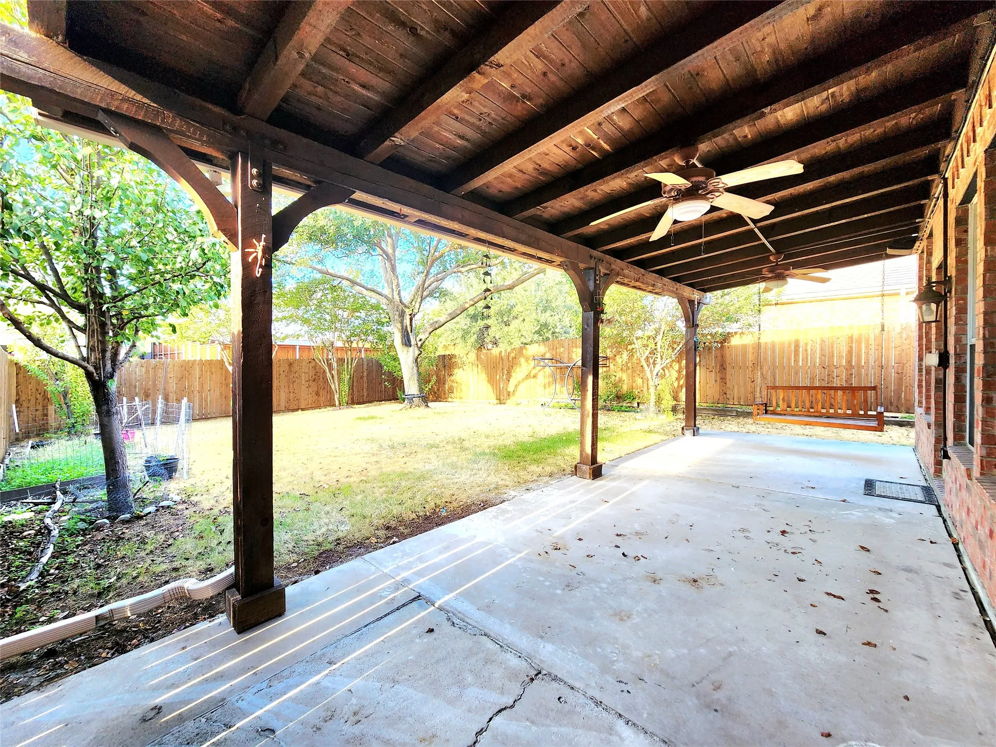 Expansive covered patio with a wood-finish ceiling, exposed beams, and multiple ceiling fans