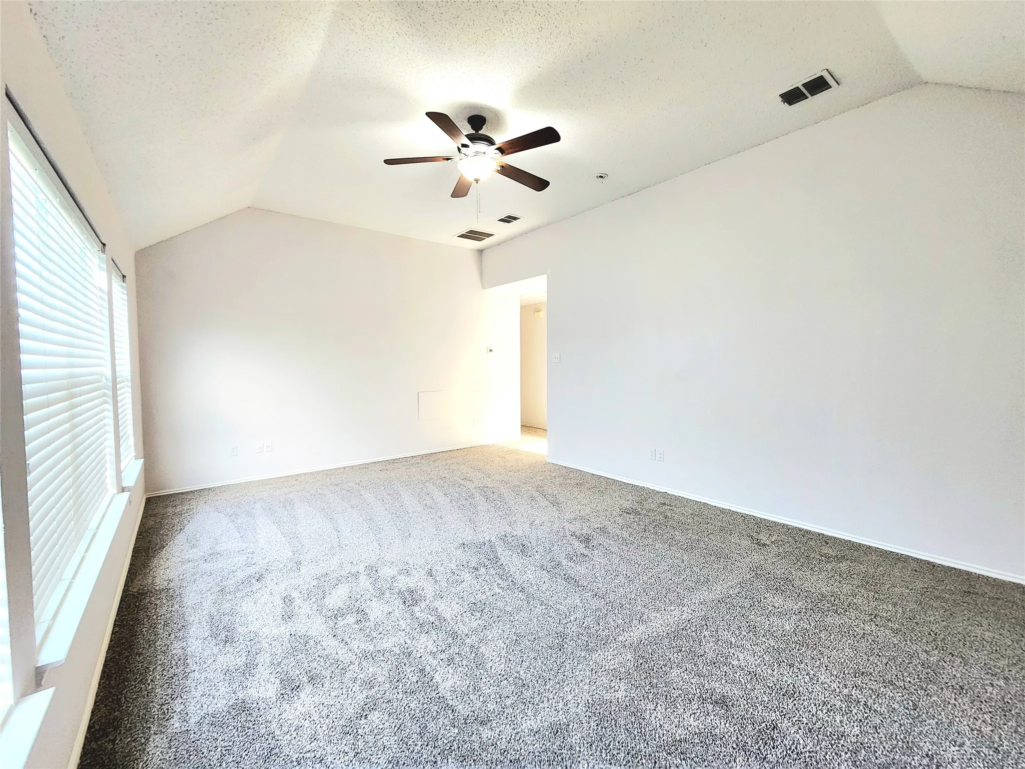 Vaulted ceiling with a ceiling fan, grey carpet flooring, and white window blinds