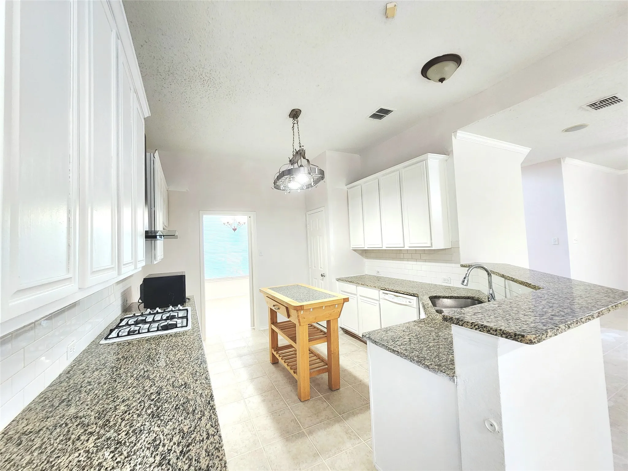 Kitchen featuring white cabinetry, stone countertops, stainless steel sink, and built-in stovetop