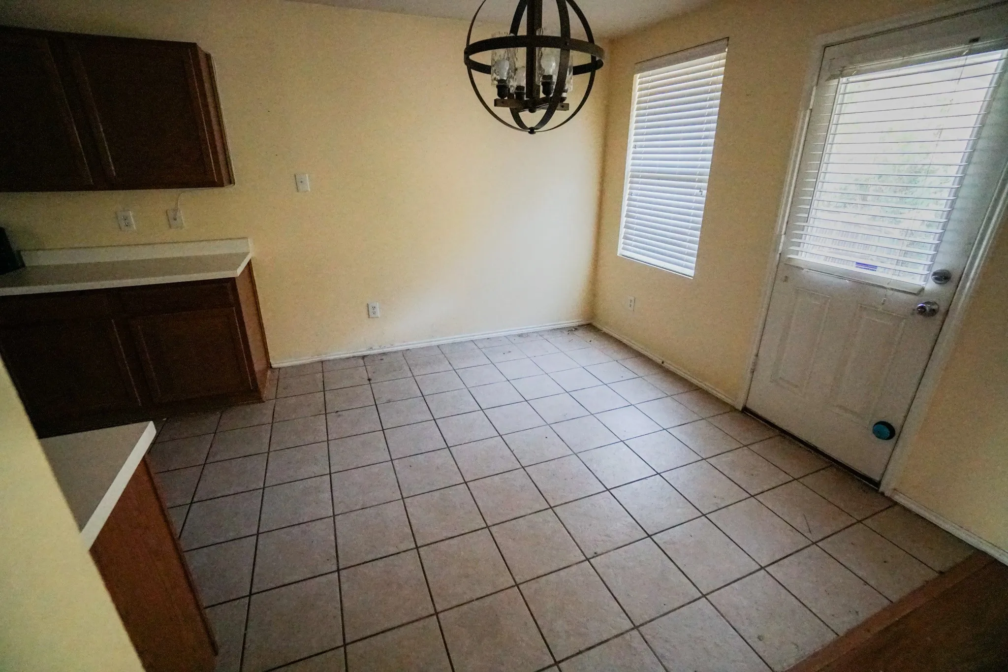 Tile flooring, wood-finish cabinetry, light-toned countertops, and a spherical light fixture