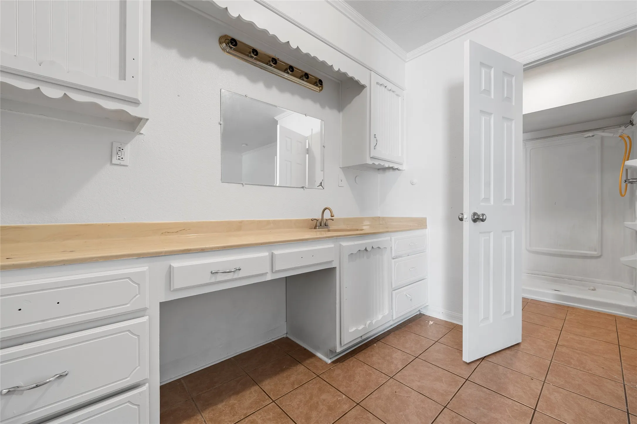 Full bath featuring vanity, tile patterned floors, crown molding, and a shower