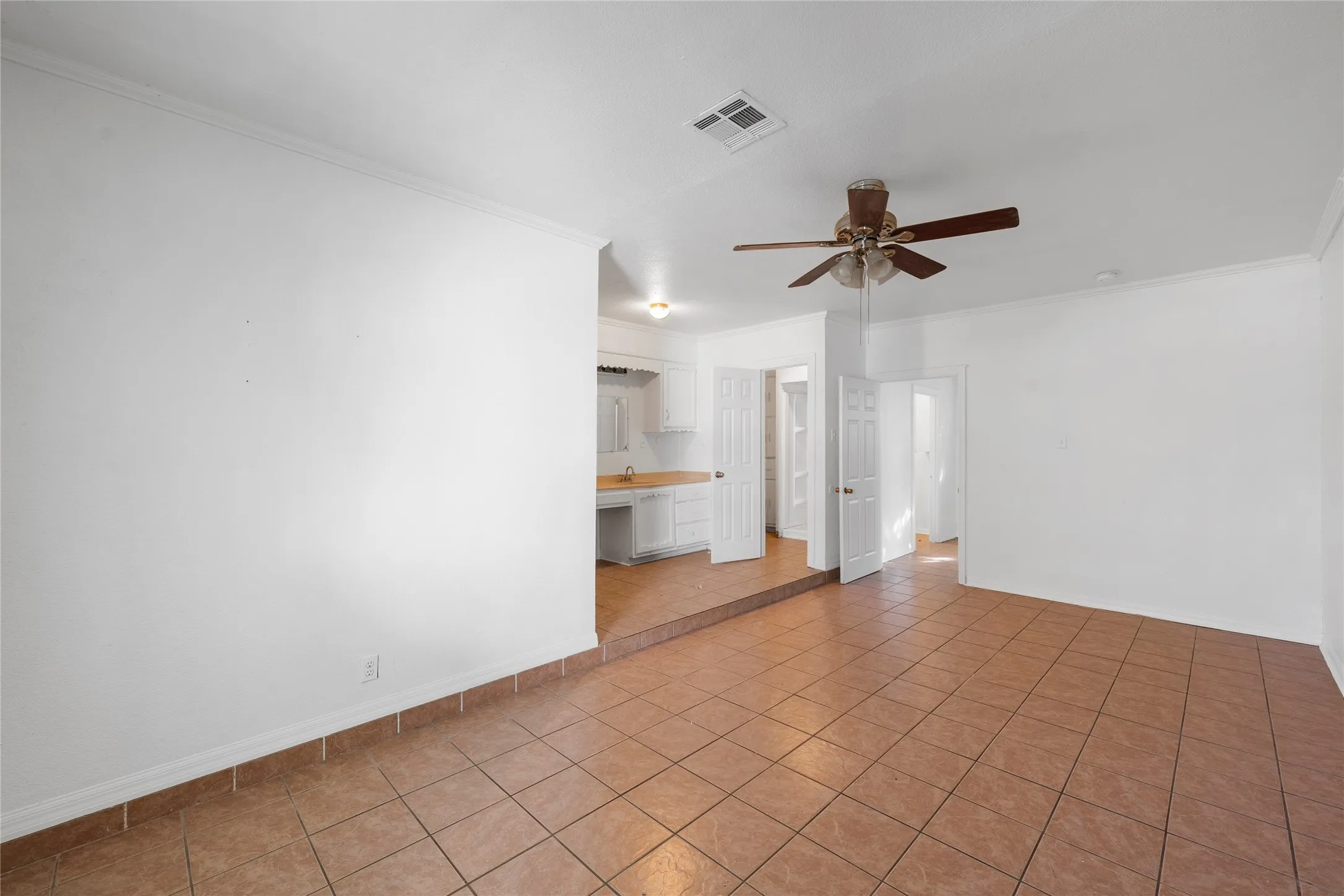 Unfurnished room with light tile patterned floors, a ceiling fan, and ornamental molding