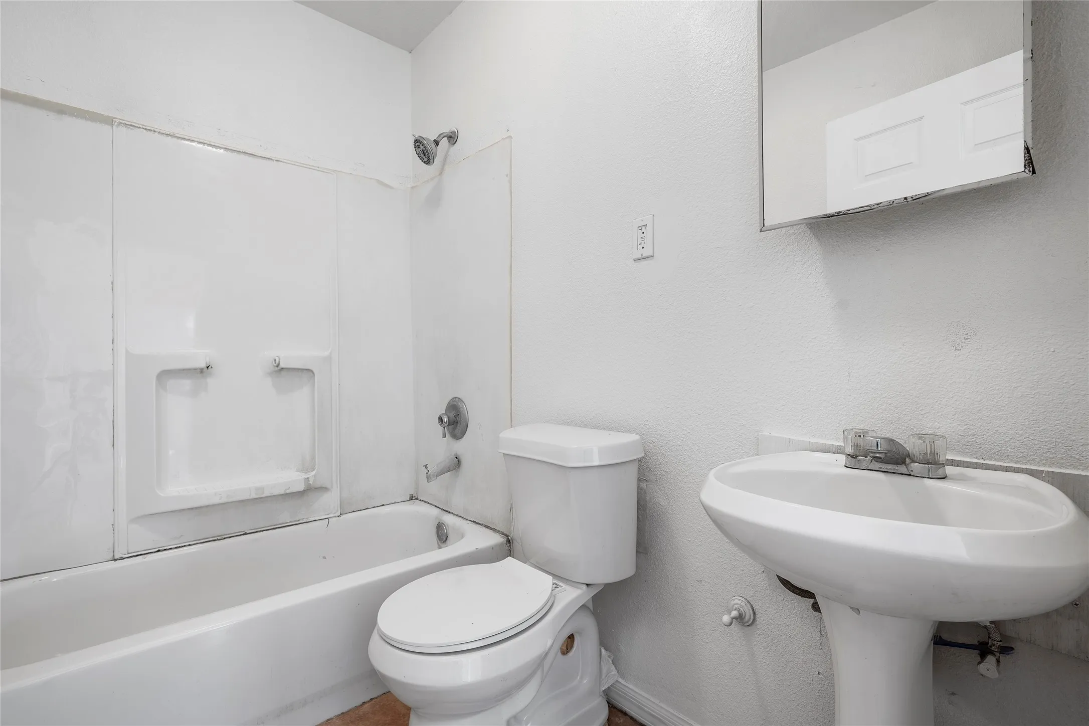 Full bathroom featuring a textured wall and shower / bathtub combination
