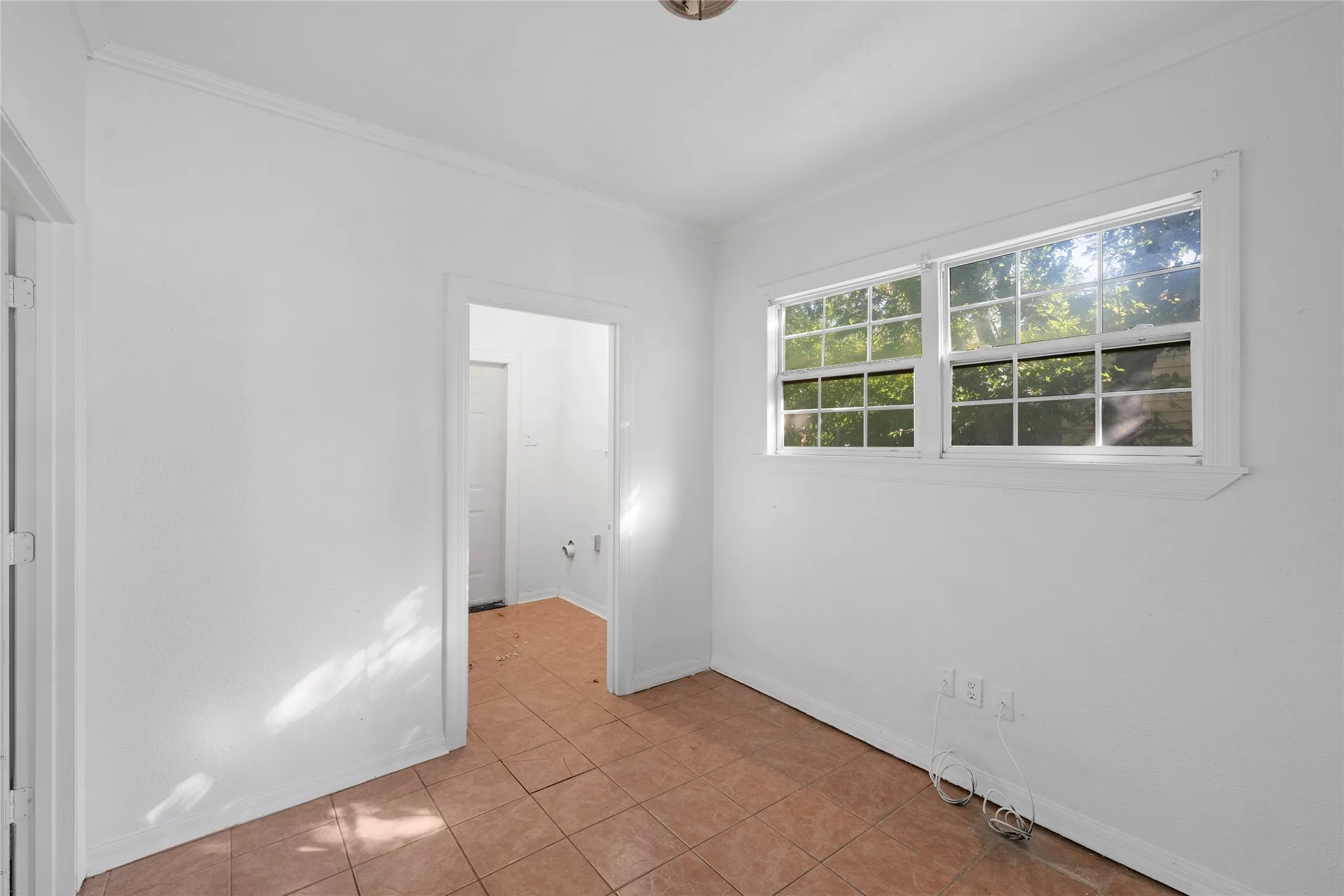 Spare room with ornamental molding and light tile patterned flooring