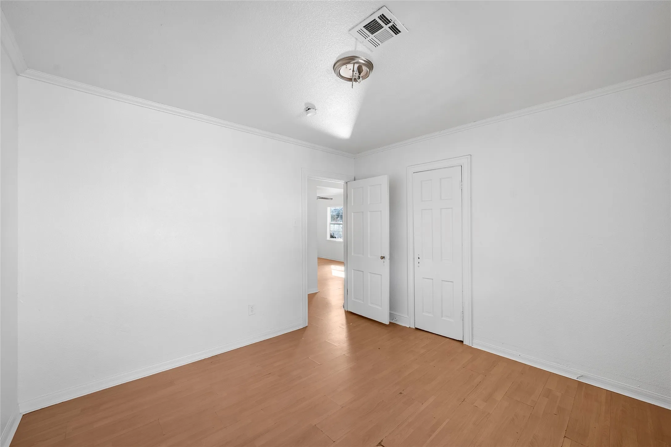 Unfurnished bedroom with light wood finished floors, ornamental molding, and a closet