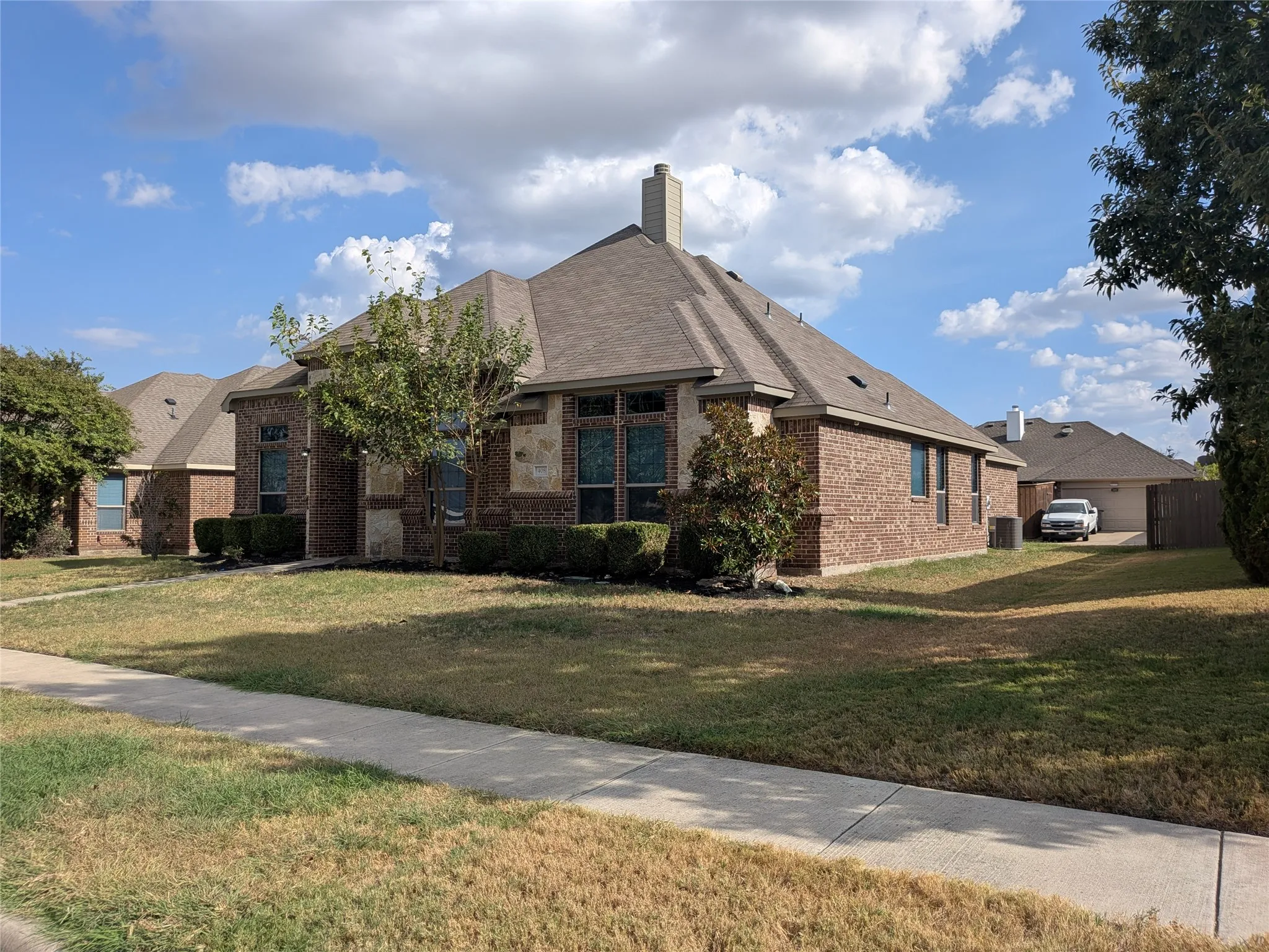 Brick and stone exterior with a hip roof, featuring multiple windows and mature landscaping