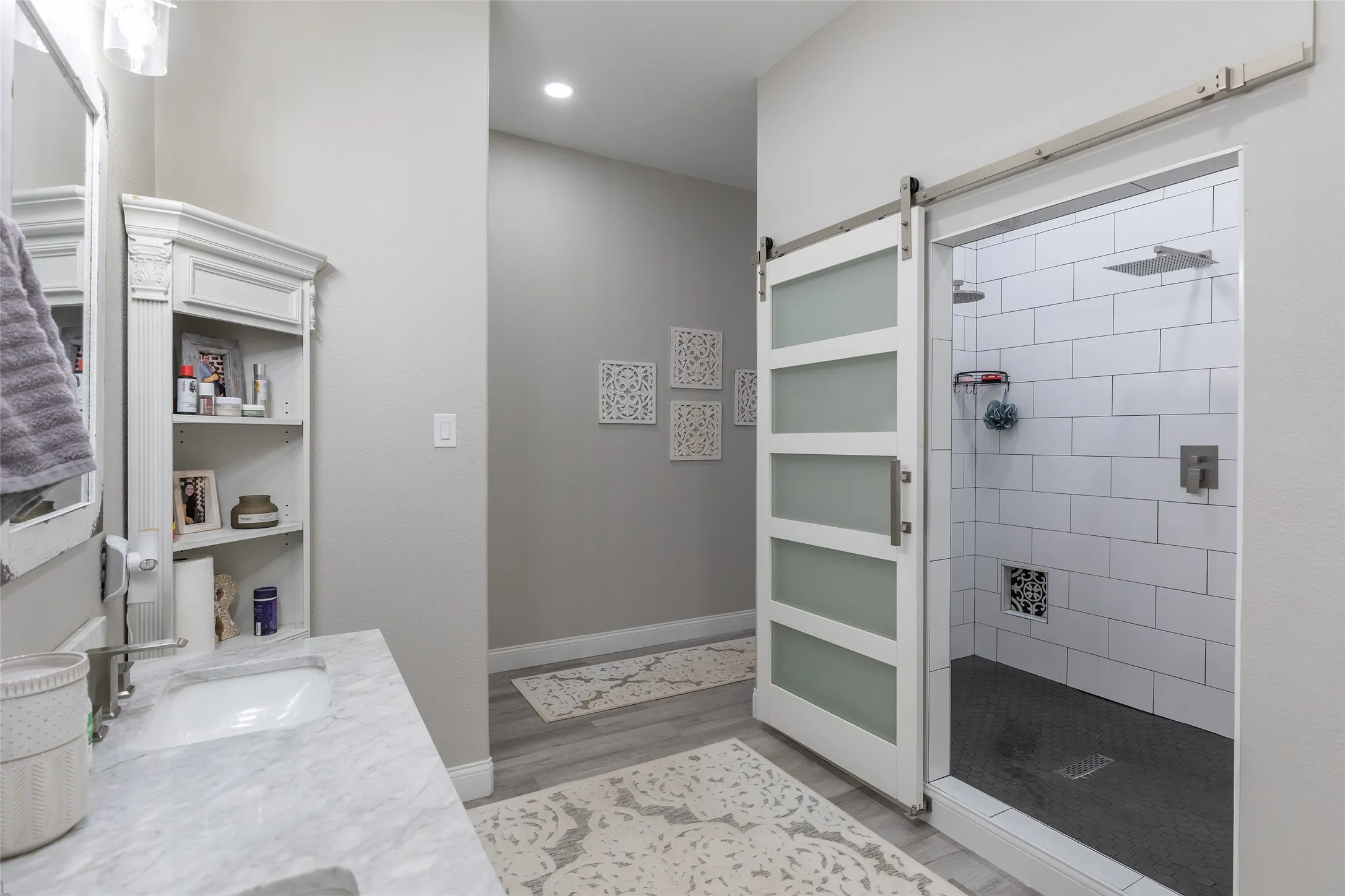 Barn door entry to a walk-in shower with subway tile surround and dark tile flooring