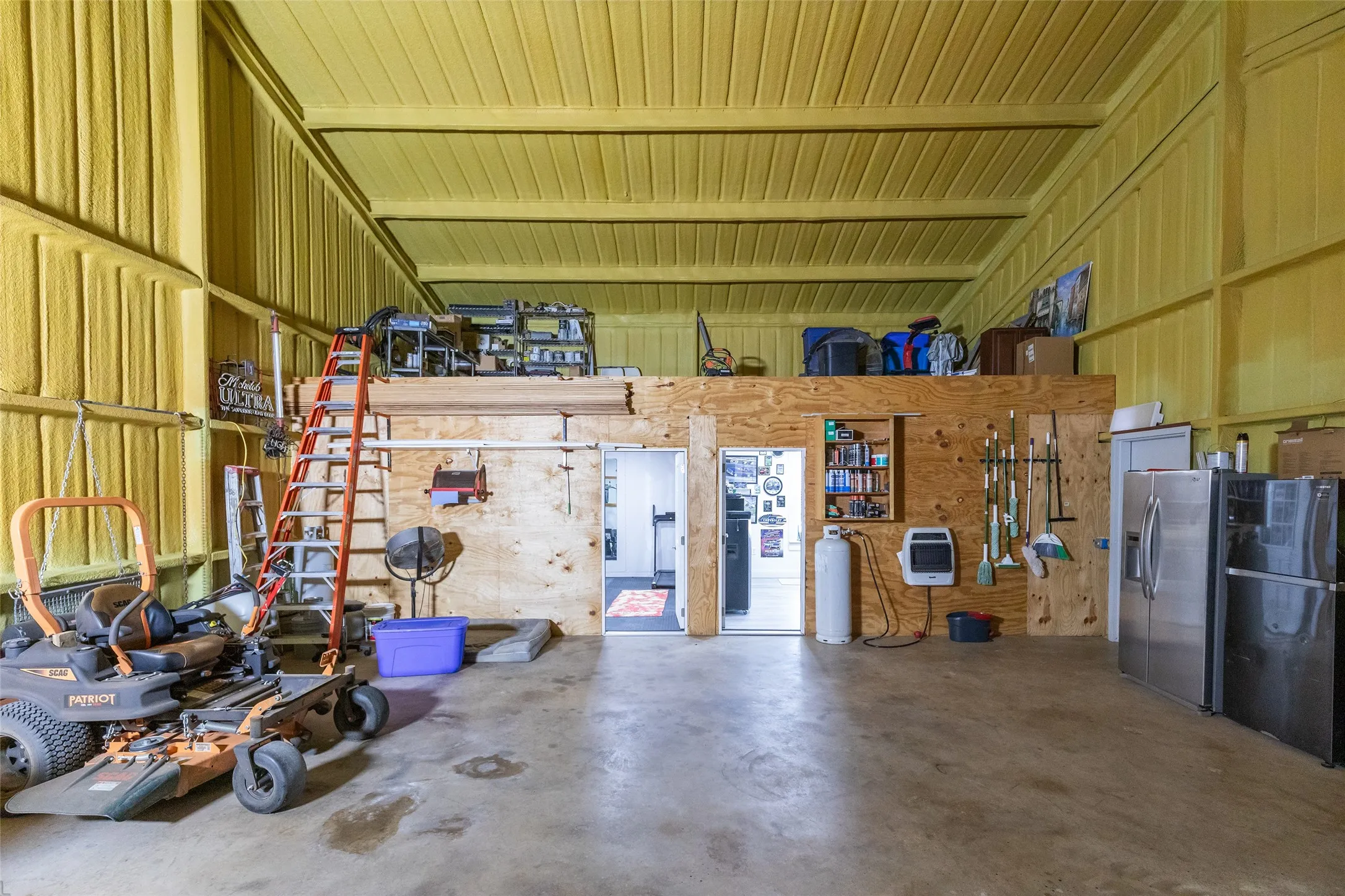 Concrete flooring with a built-in loft space, exposed beam ceiling, and insulated walls