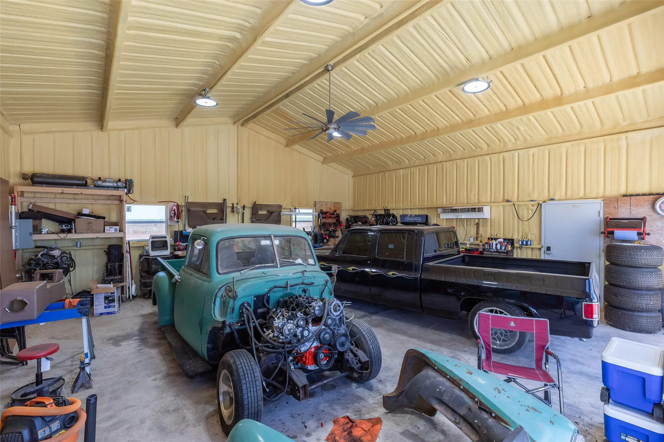 Spacious garage with exposed beam ceiling, bright overhead lighting, and concrete flooring