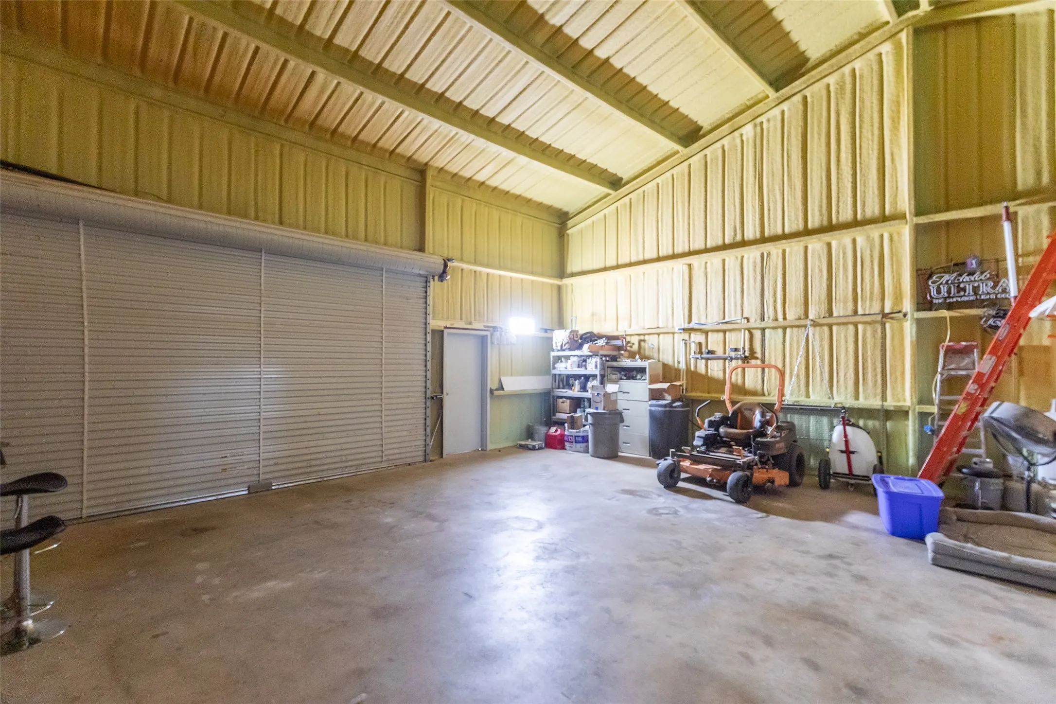 Spacious utility building featuring a concrete floor, high ceilings, and a large roll-up door