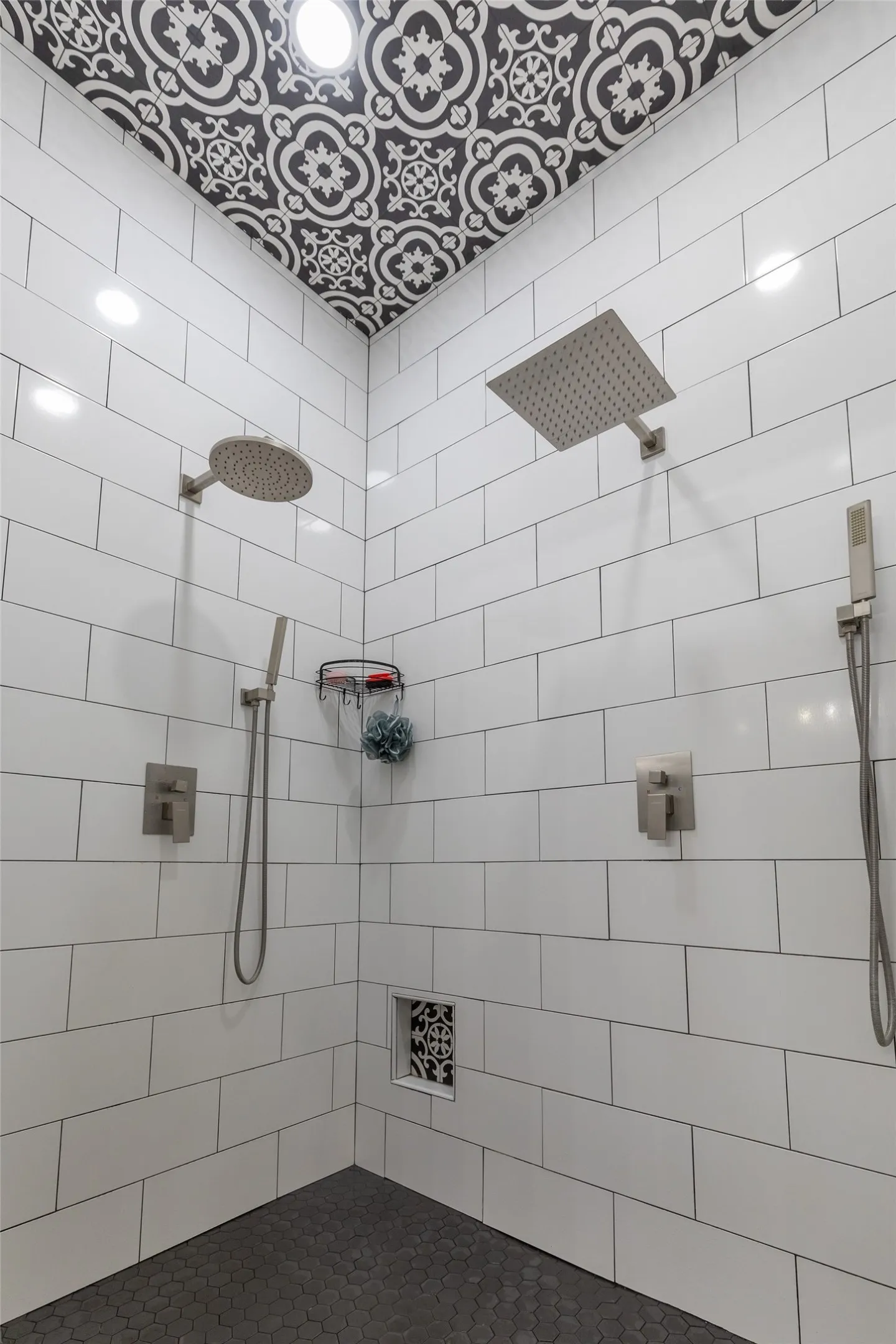Walk-in shower featuring dual shower heads, white subway tile walls, a patterned ceiling, and dark hexagon tile flooring