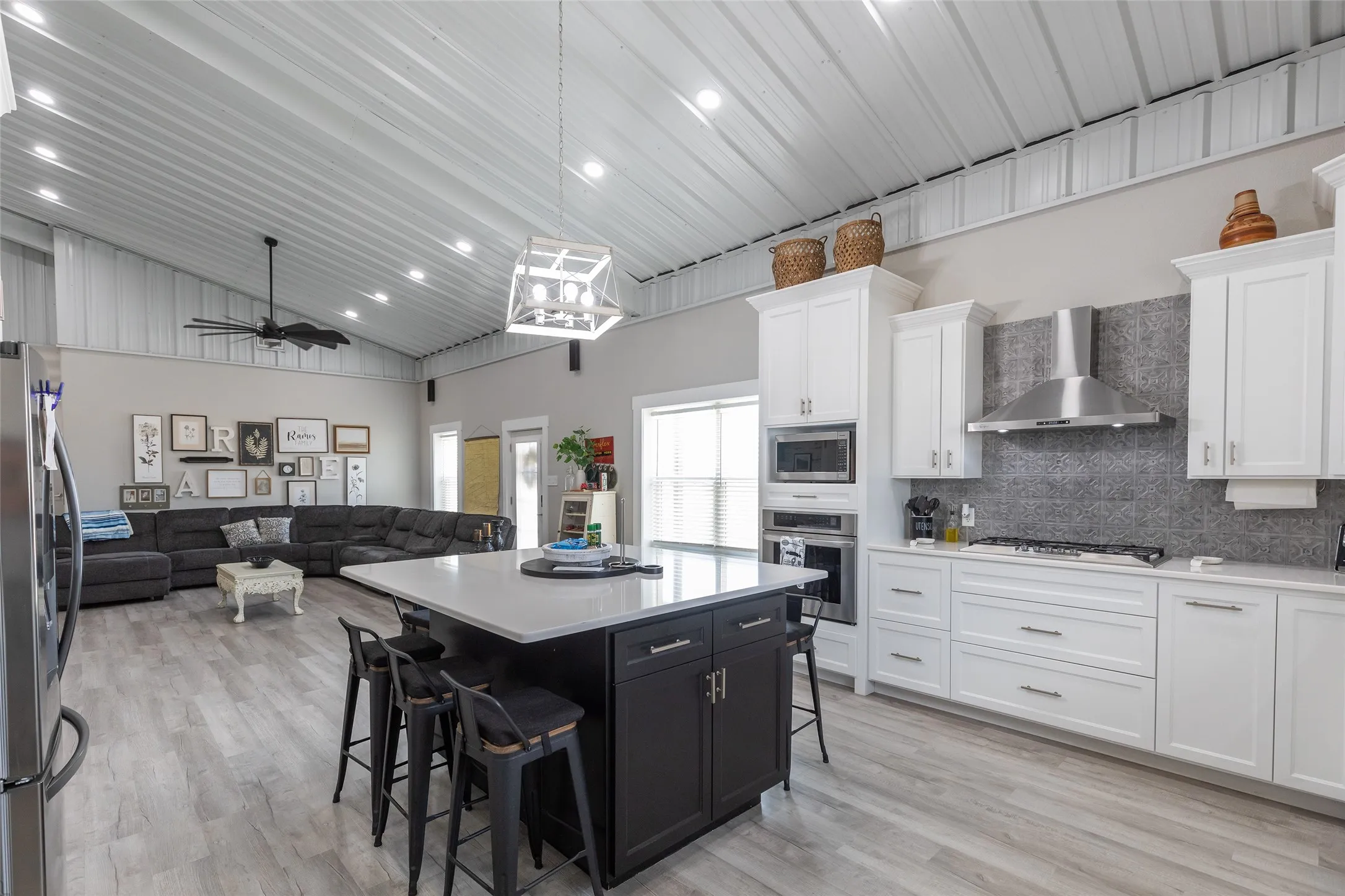 Open-concept living space featuring wood-finish flooring, a vaulted ceiling, and a kitchen island with seating