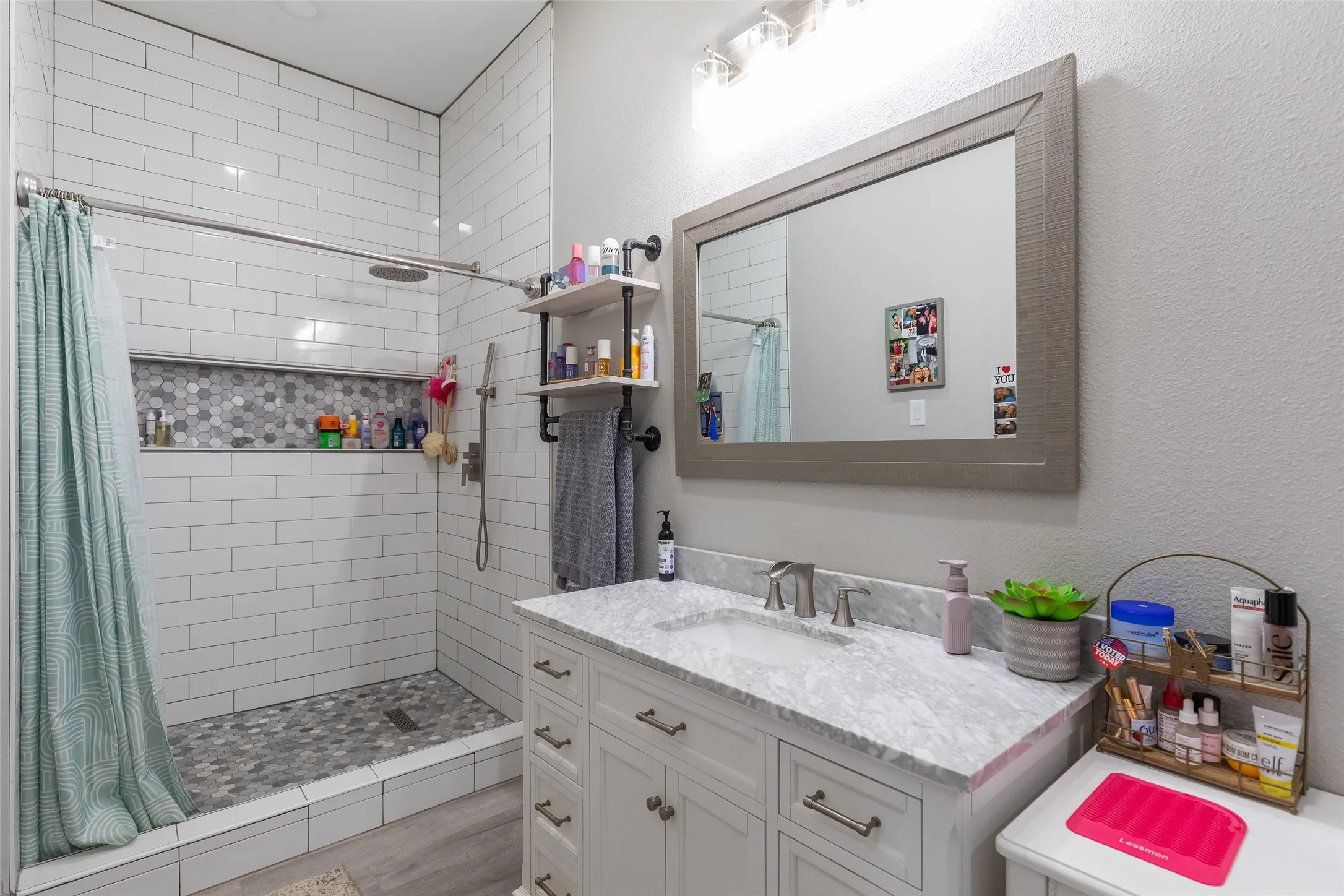 Walk-in shower with subway tile surround, hexagon tile flooring, and a recessed niche