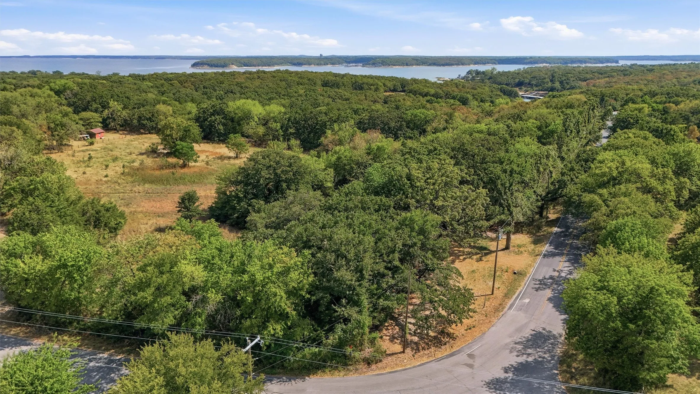Expansive treed landscape with a paved road and partial water frontage