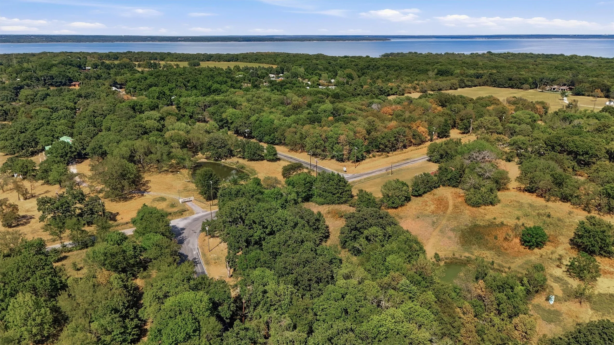 Expansive acreage featuring mature trees, a private pond, and paved road access