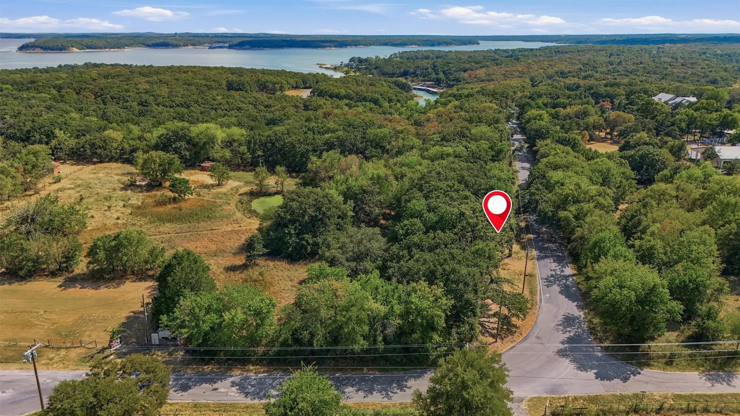 Wooded property featuring a pond, paved road frontage, and proximity to a large body of water