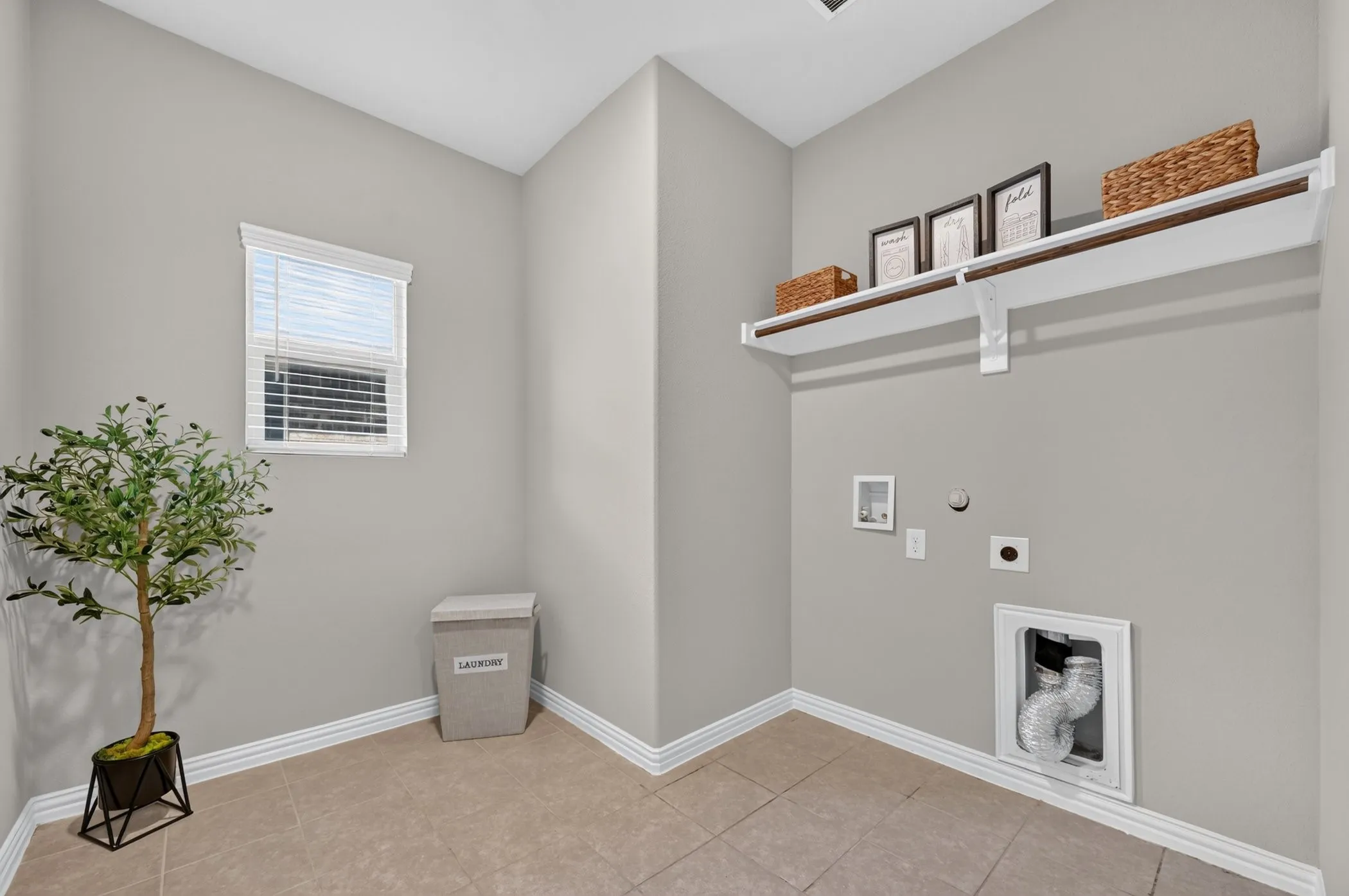 Tiled flooring with white baseboards, a window with blinds, and a built-in shelf with a hanging rod