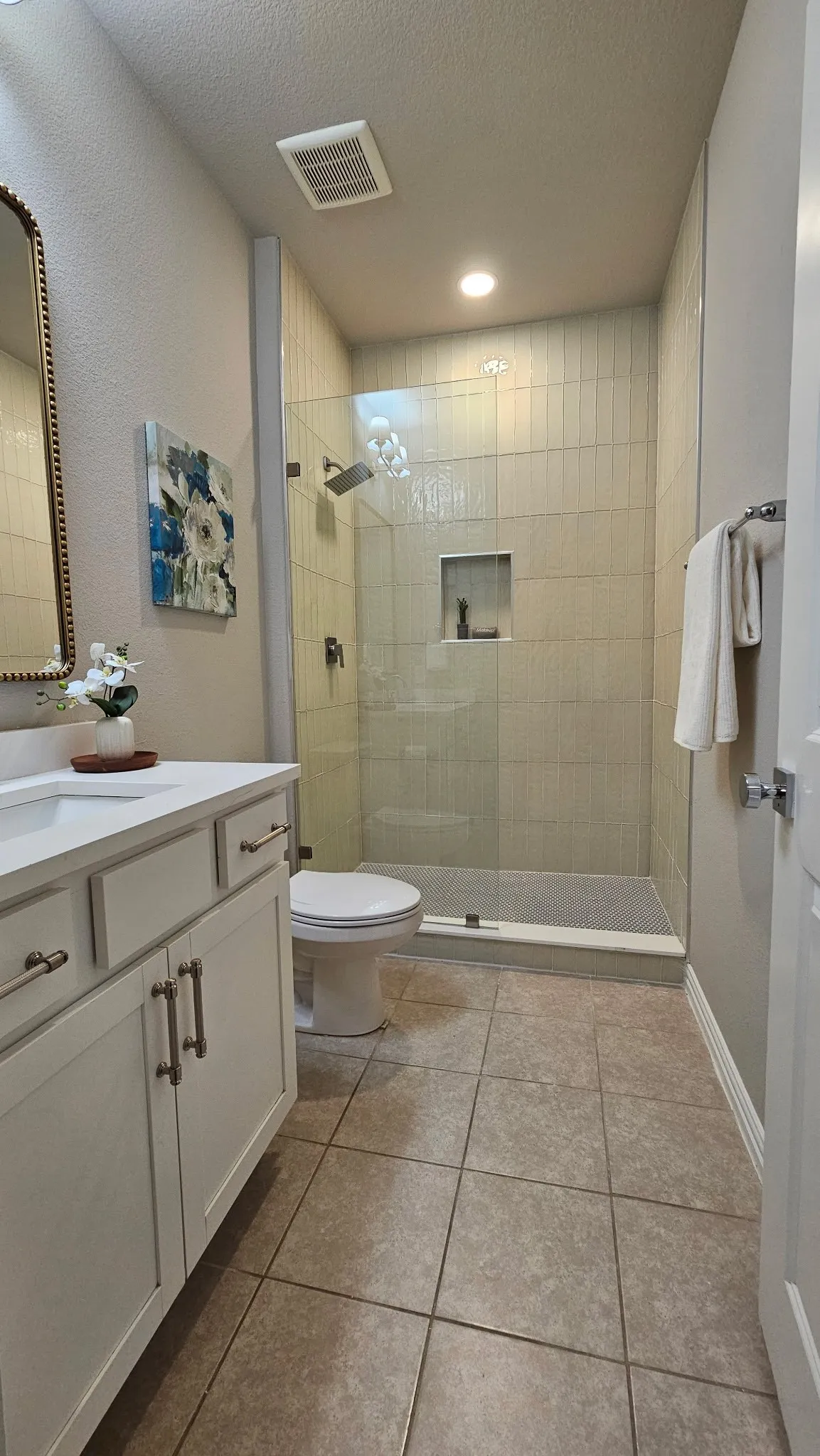 White vanity with a single sink, light-toned countertop, and brushed nickel hardware