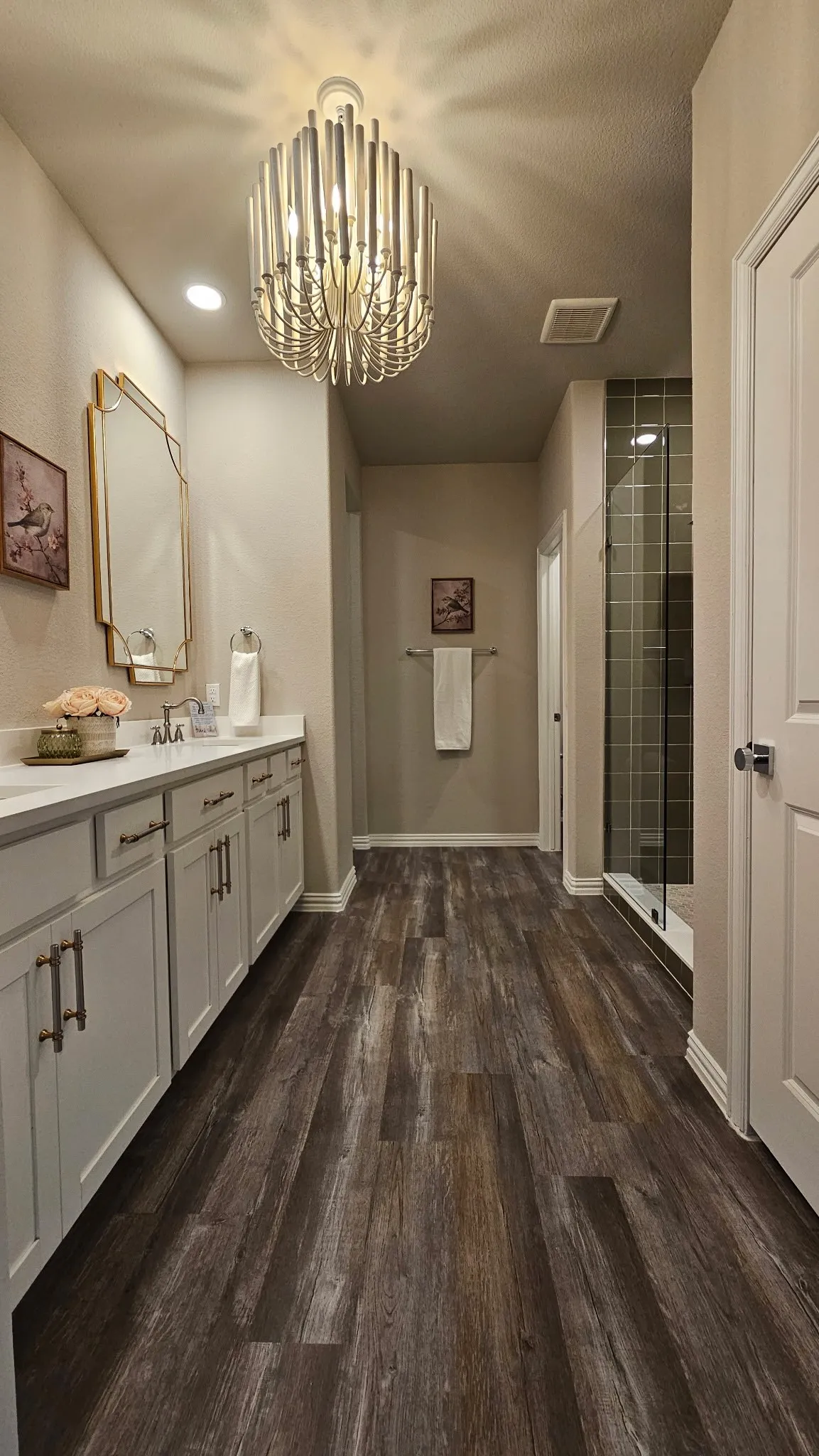 Wood-finish flooring leading to a walk-in shower with dark subway tile