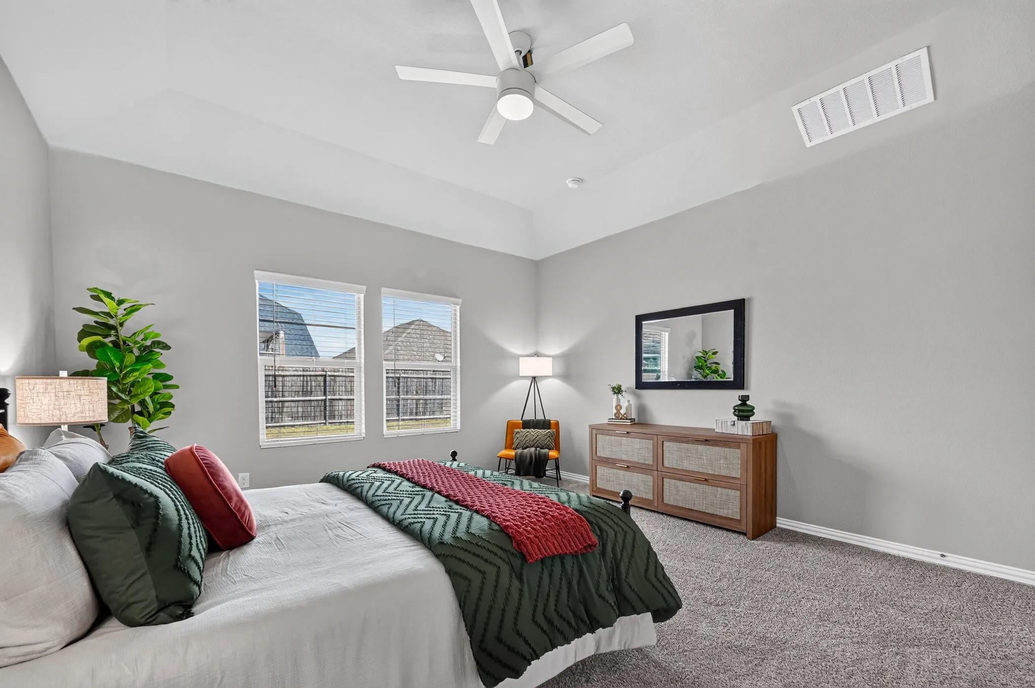 Tray ceiling with a ceiling fan, two windows, and gray carpeting