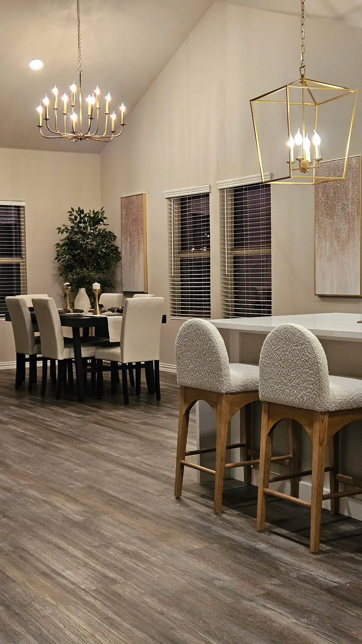 Vaulted ceiling with dual chandeliers, wood-finish flooring, and multiple windows