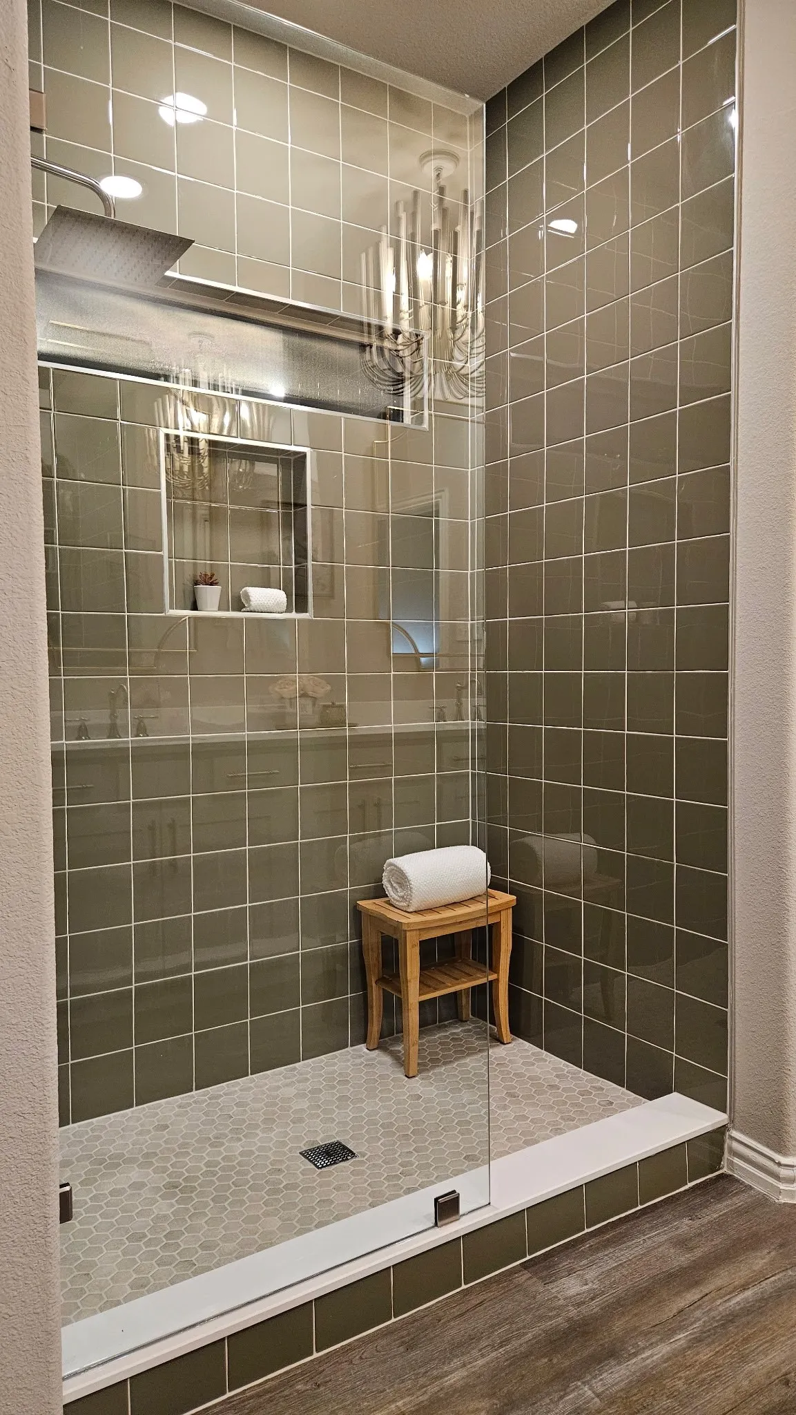 Walk-in shower with full glass enclosure, square wall tiles, integrated niche, and hexagonal floor tiles