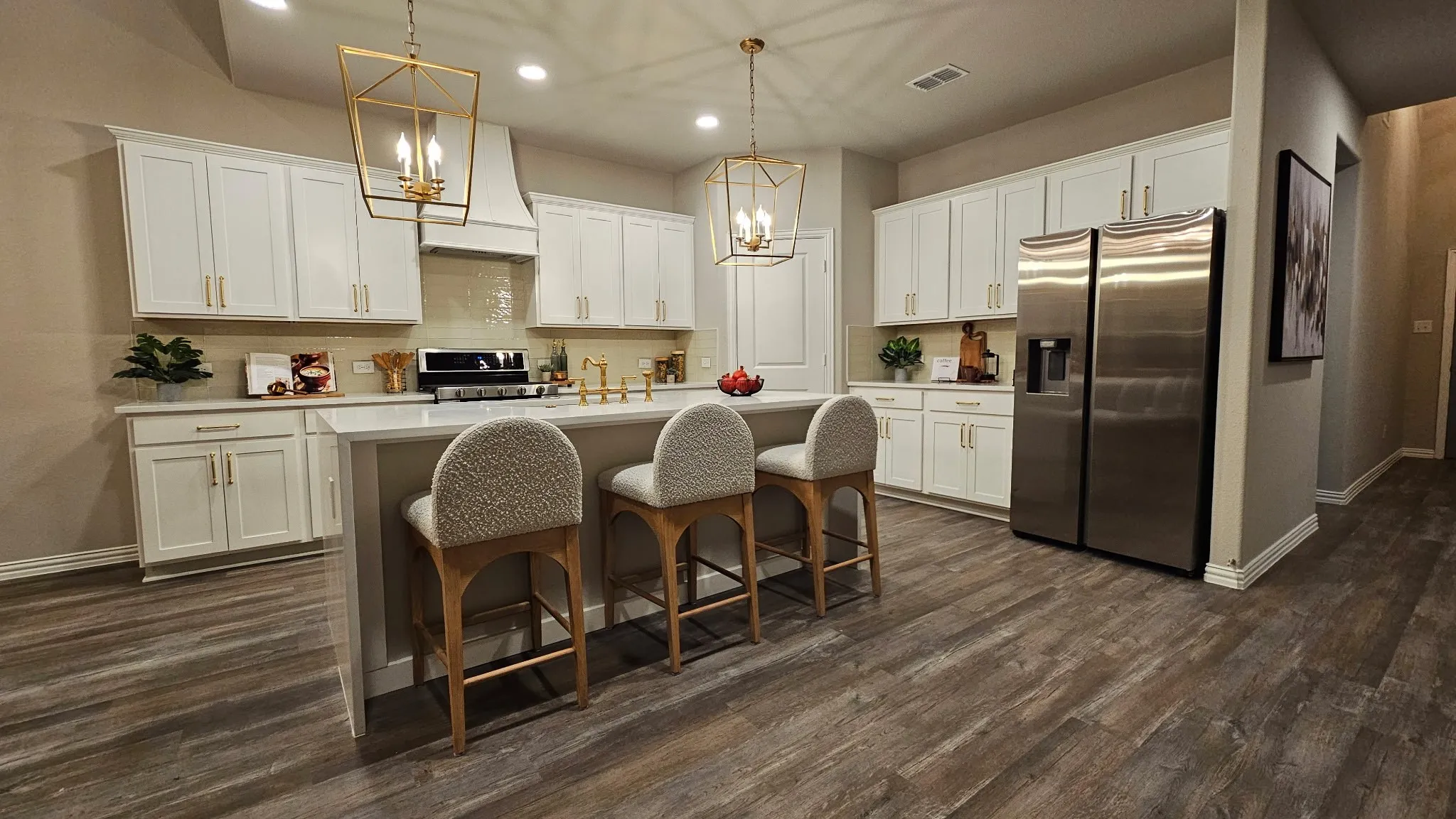 Spacious kitchen featuring an island with countertop seating, white cabinetry, a stainless steel refrigerator, and wood-finish flooring