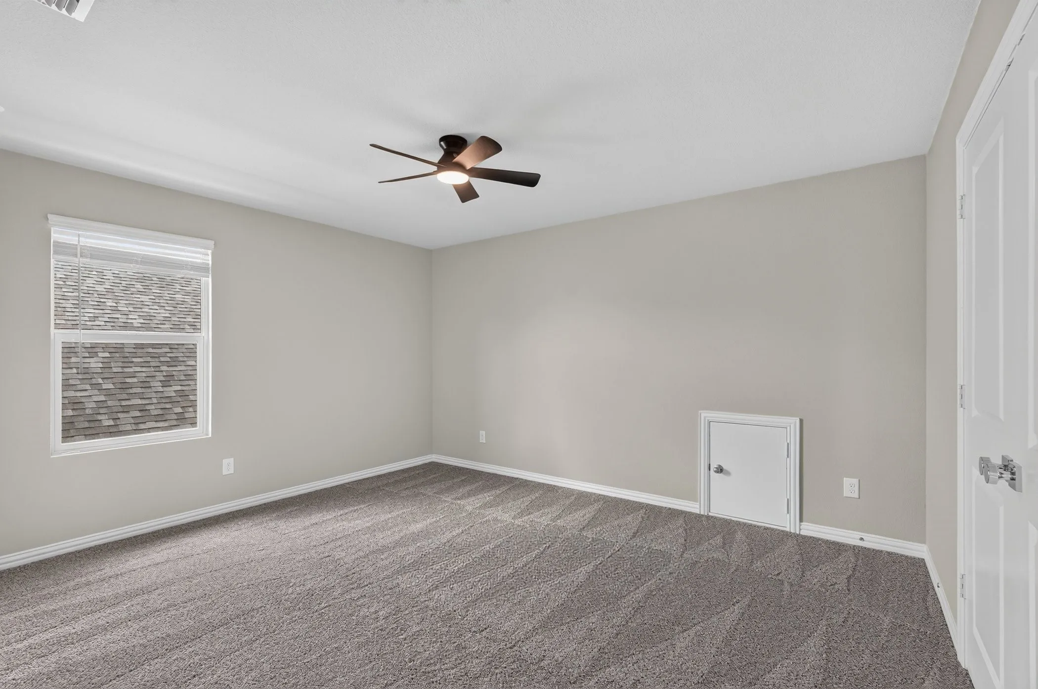 Spacious room featuring neutral carpeting, a ceiling fan, and a window with blinds
