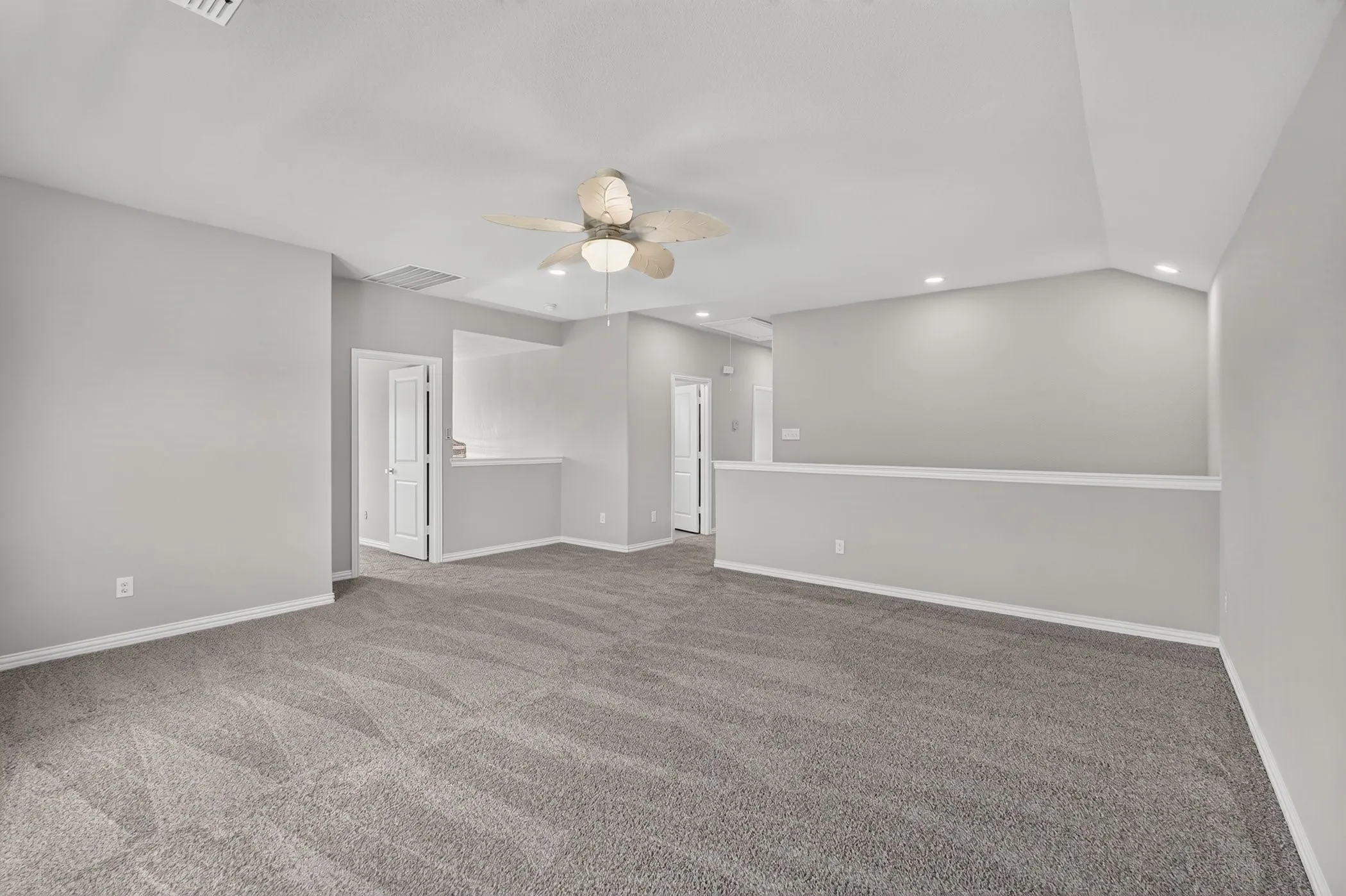 Spacious room featuring carpeting, neutral-toned walls, vaulted ceilings, recessed lighting, and a ceiling fan