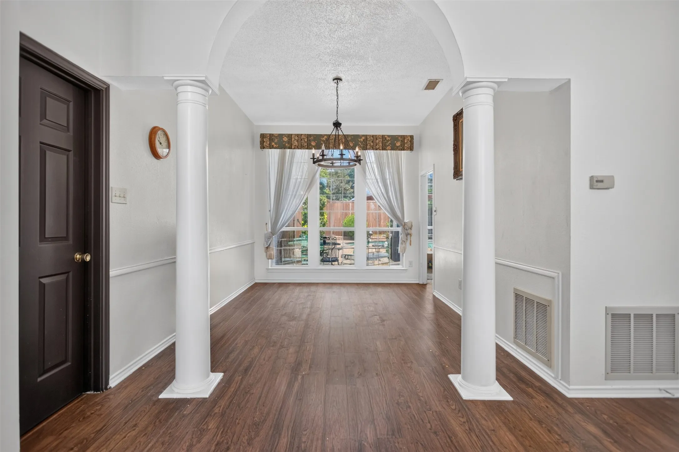 Wood-finish flooring, decorative white columns, and wainscoting