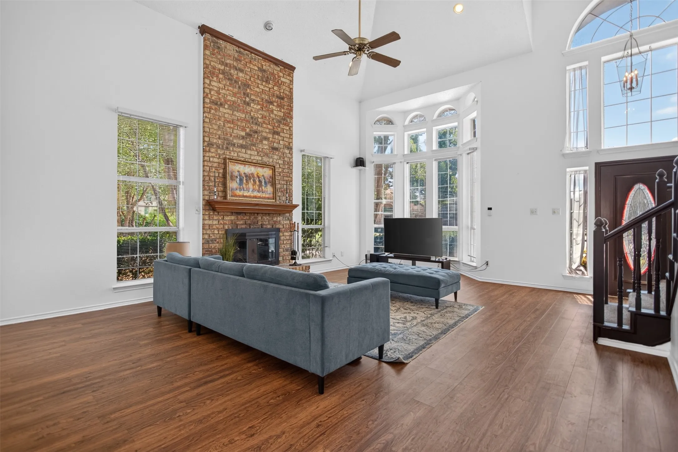Expansive living space featuring wood-finish flooring and a vaulted ceiling with a ceiling fan