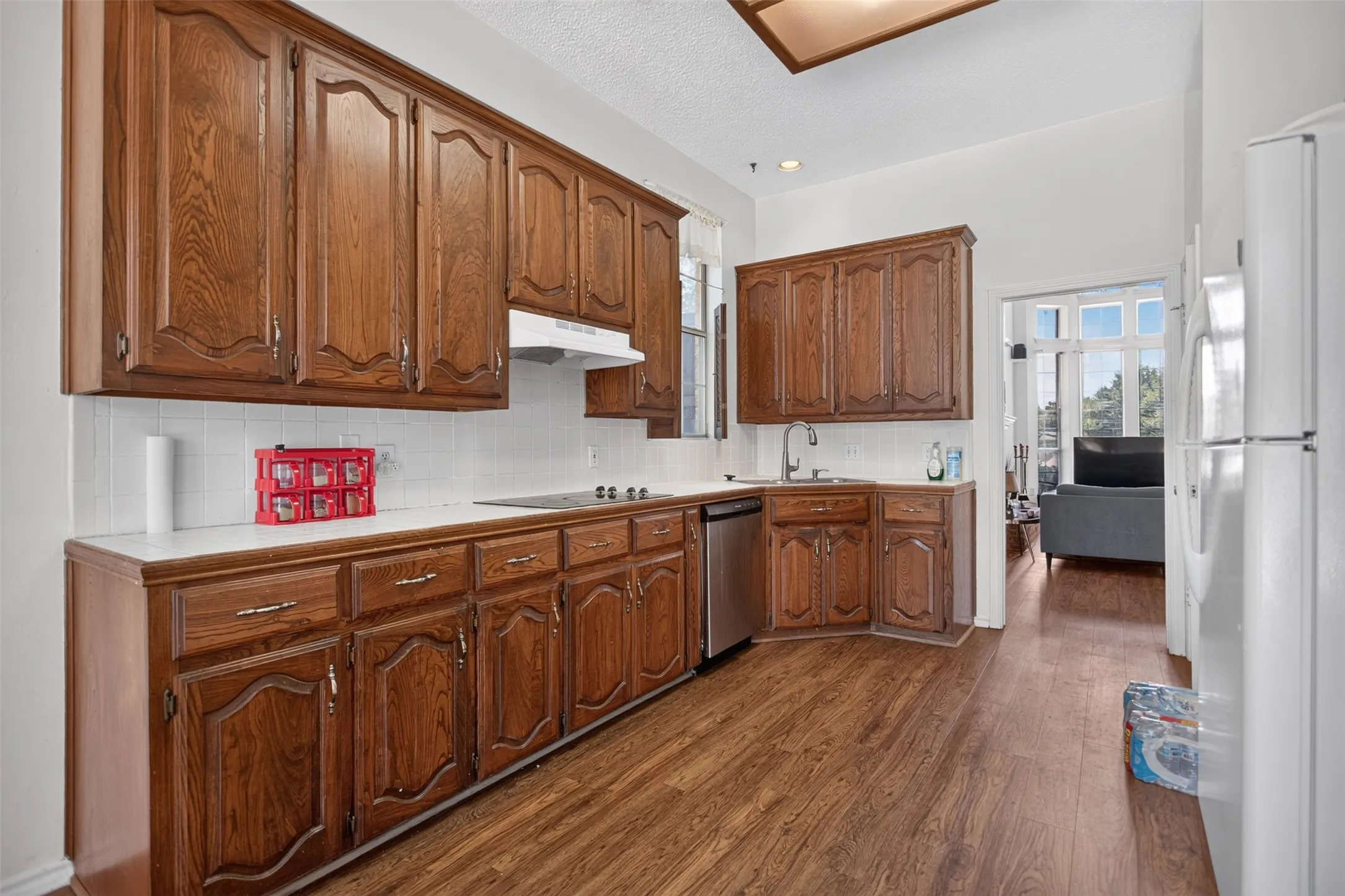 Kitchen with wood-finish flooring, extensive wood cabinetry, white countertops, and a tile backsplash