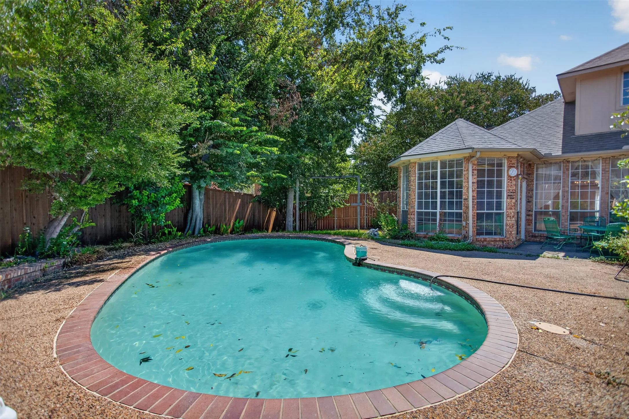 Kidney-shaped swimming pool with brick coping and aggregate decking