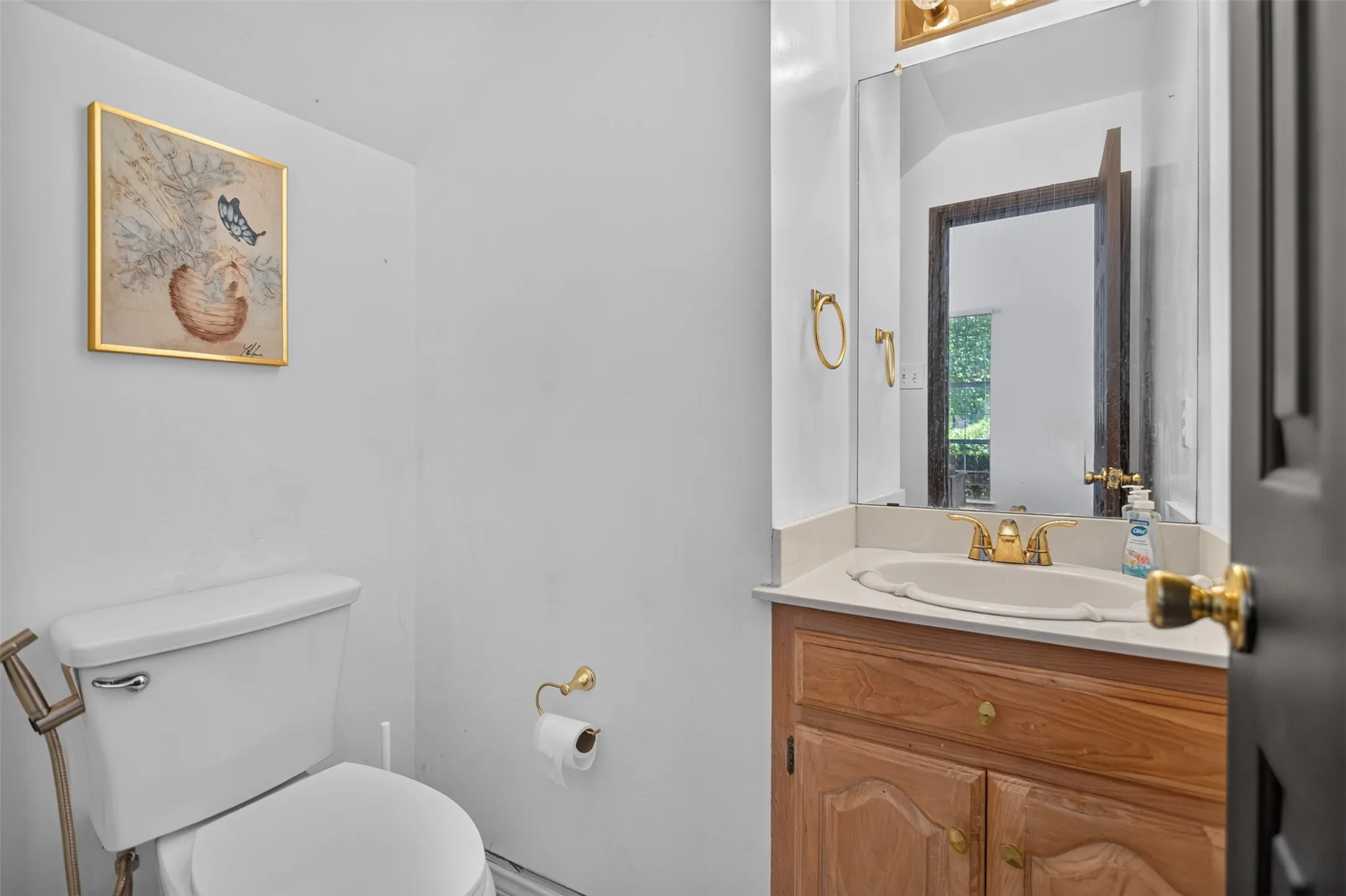 Vanity with wood-finish cabinetry, integrated sink, and gold-tone faucet