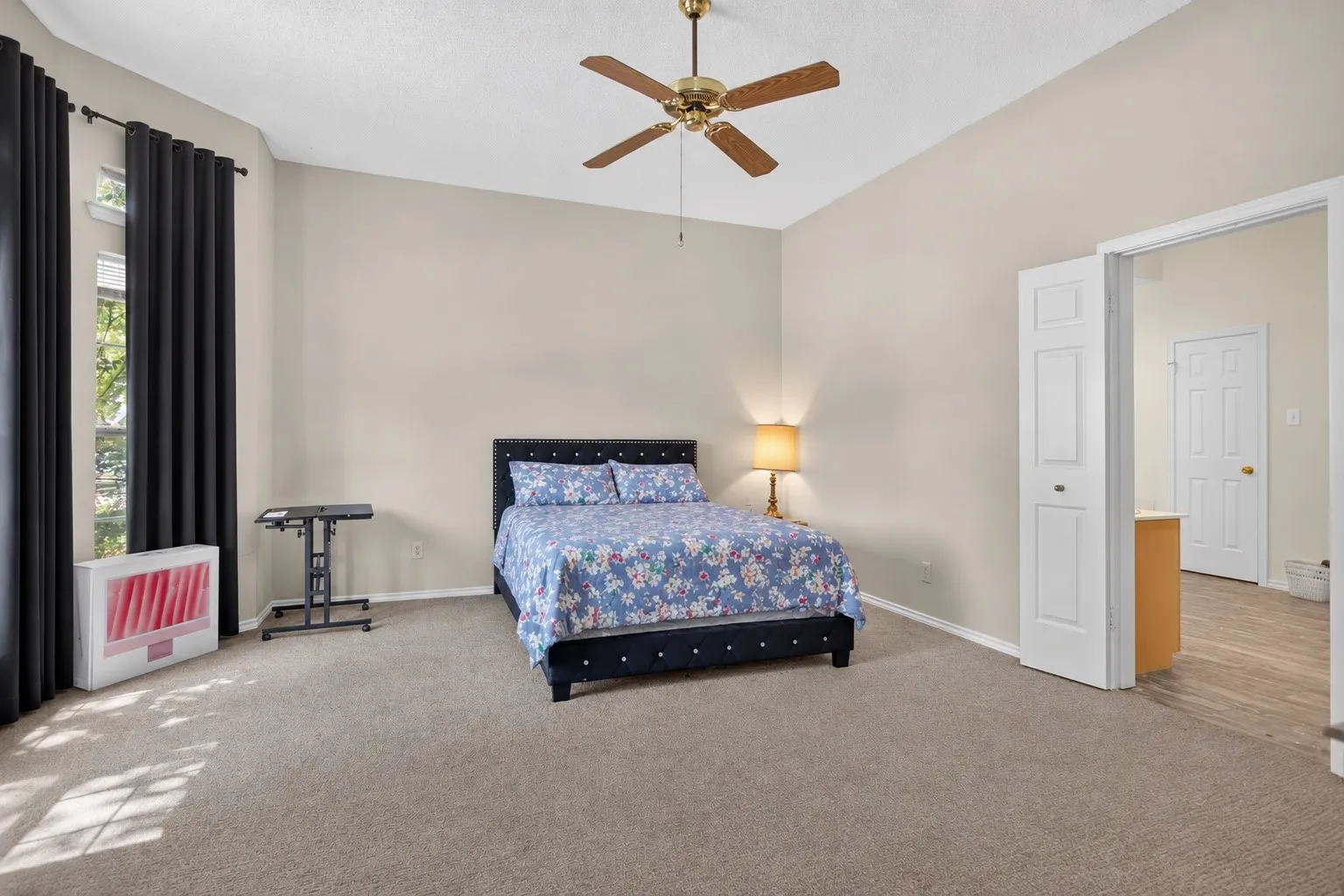 Vaulted ceiling with a ceiling fan, carpet flooring, window with dark curtains, and a white interior door